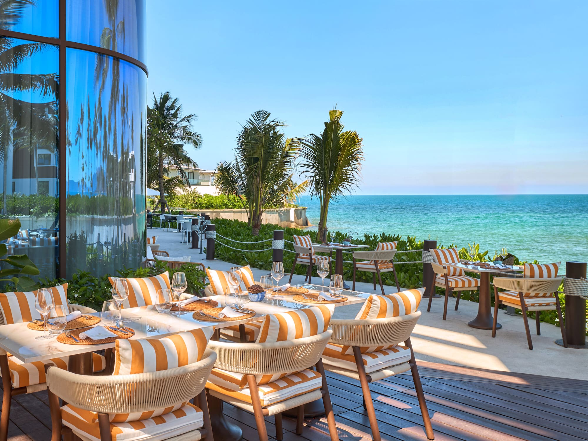 a restaurant with tables and chairs on a deck overlooking the ocean
