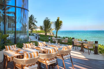 a restaurant with tables and chairs on a deck overlooking the ocean
