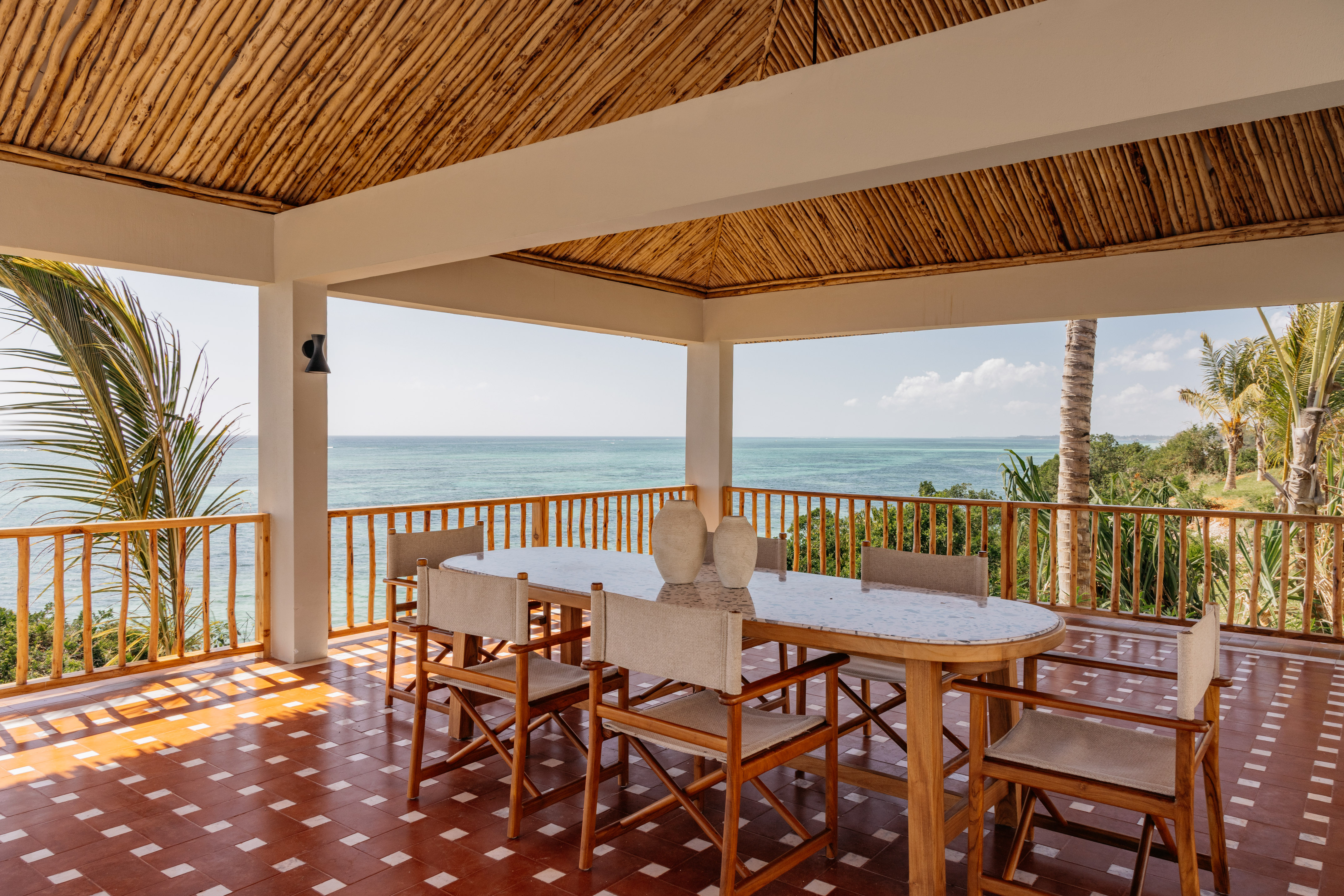 Oceanfront dining patio with bamboo ceiling and wooden furniture.