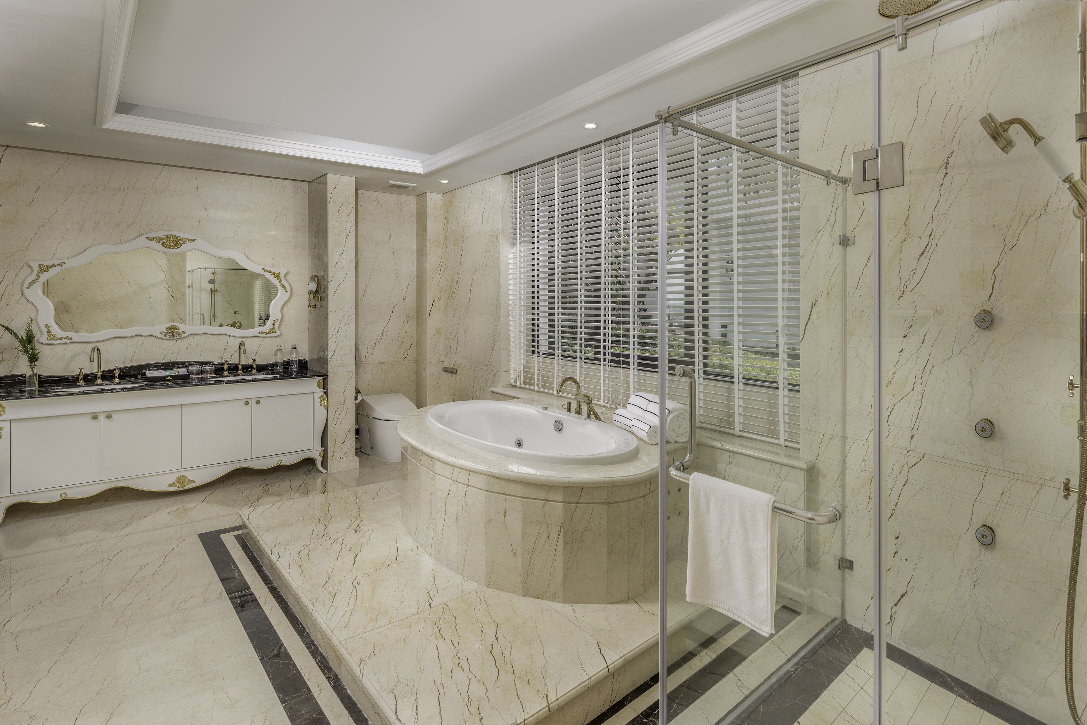 Luxurious marble bathroom with jetted tub, glass shower, and double vanity.