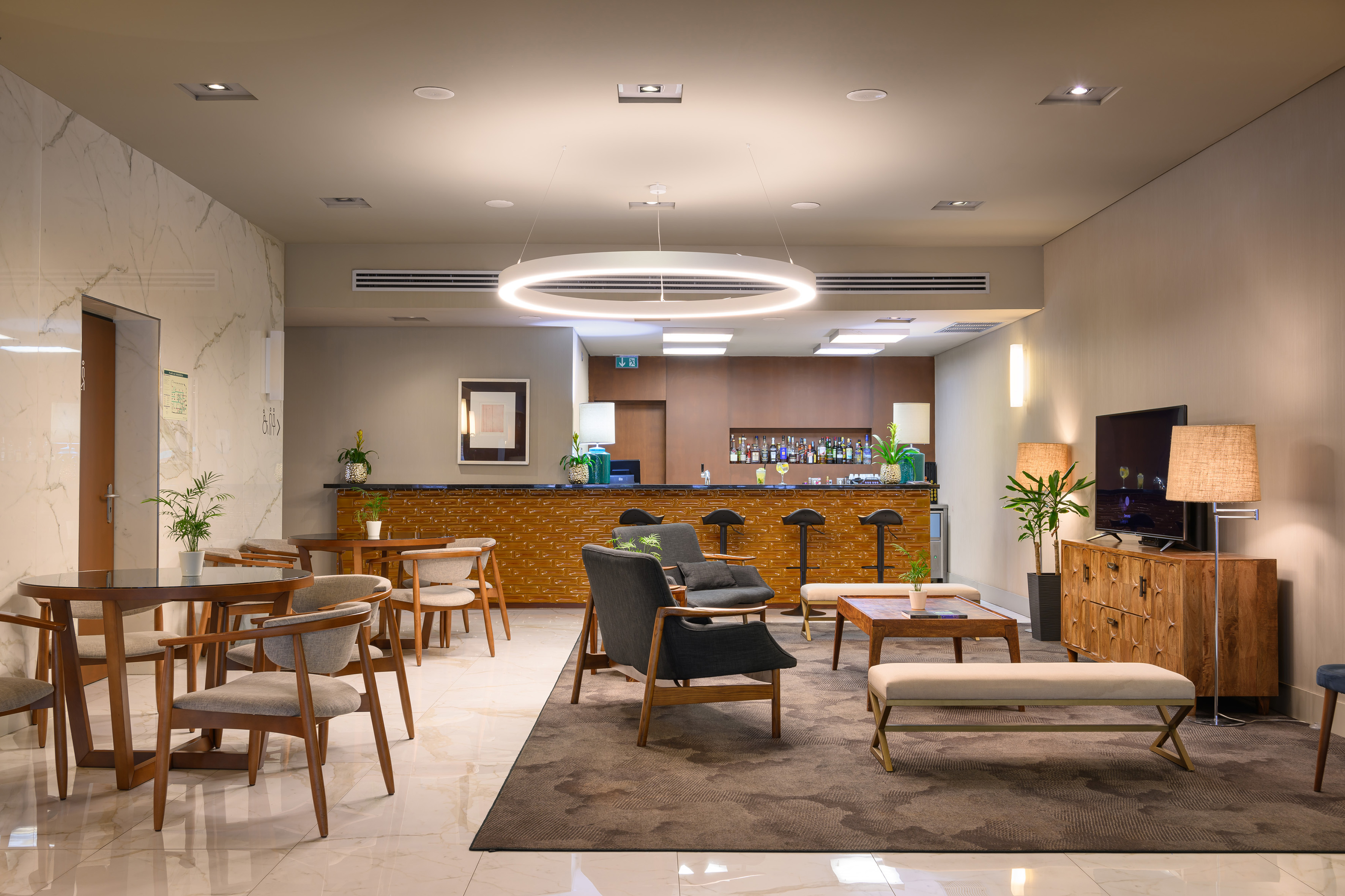Modern hotel lounge bar with varied seating and ambient lighting.