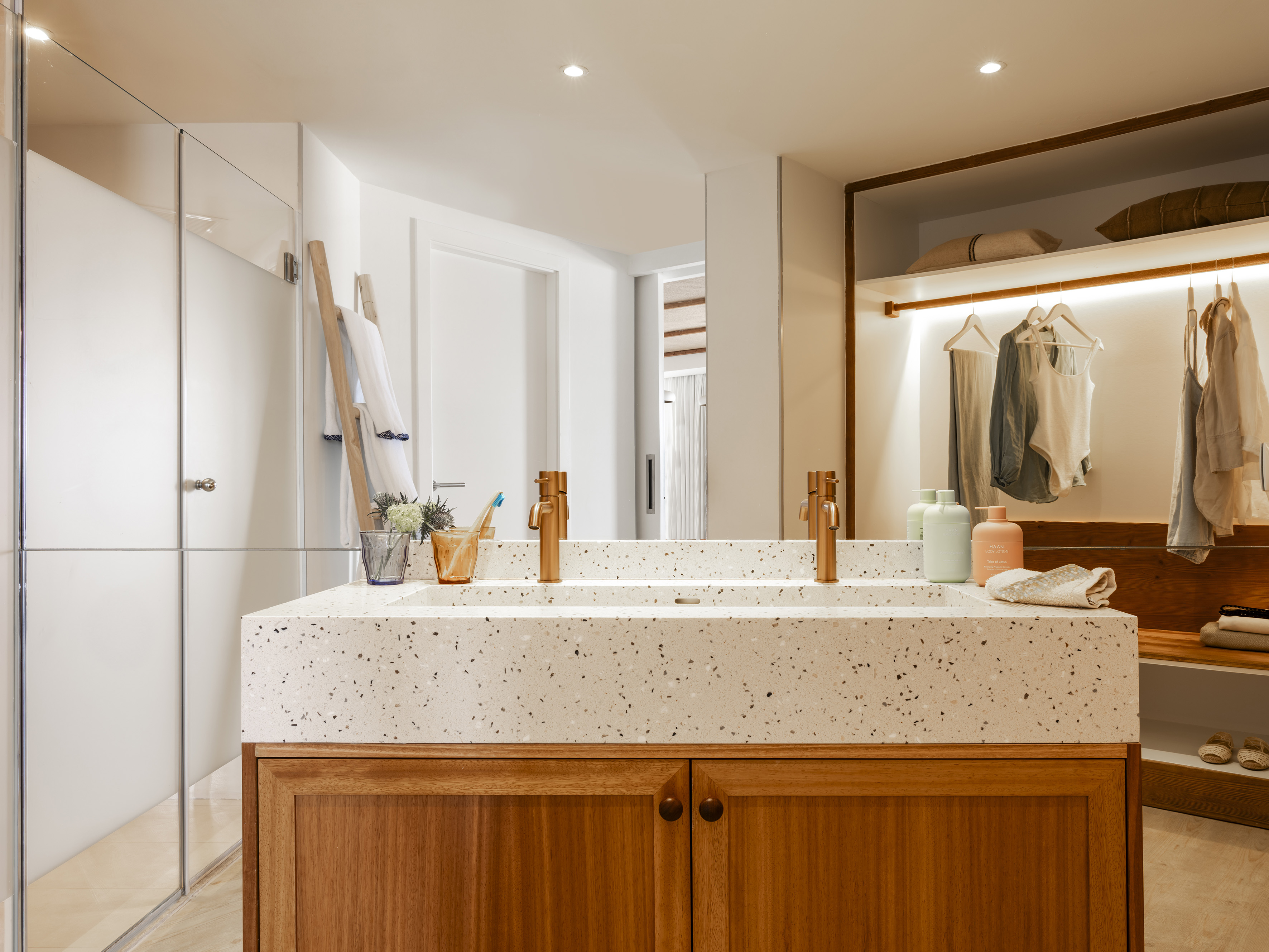 Modern bathroom with double terrazzo vanity, wood cabinet, lit closet.