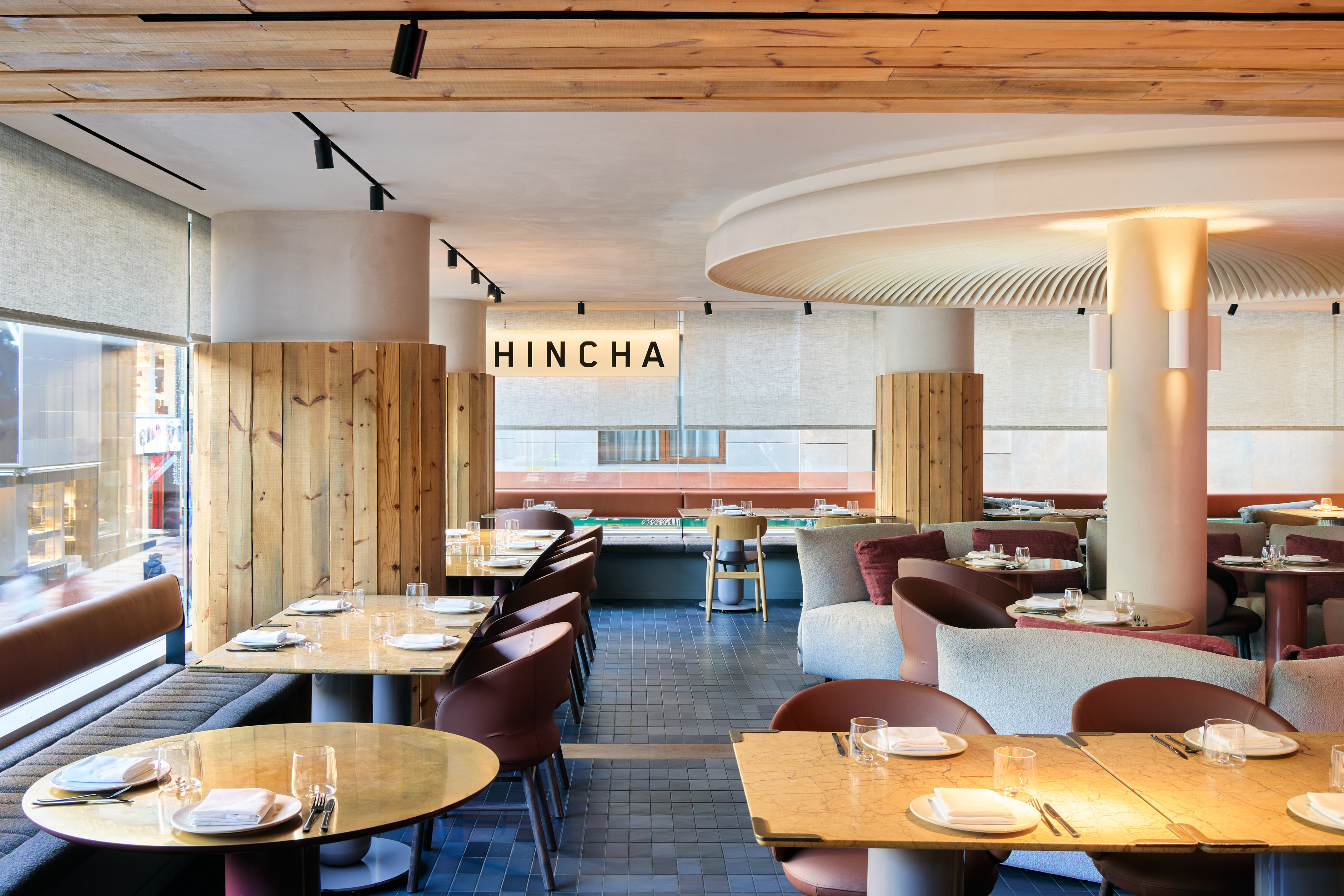Contemporary Hincha restaurant with wood panels, gold tables, plush seating.