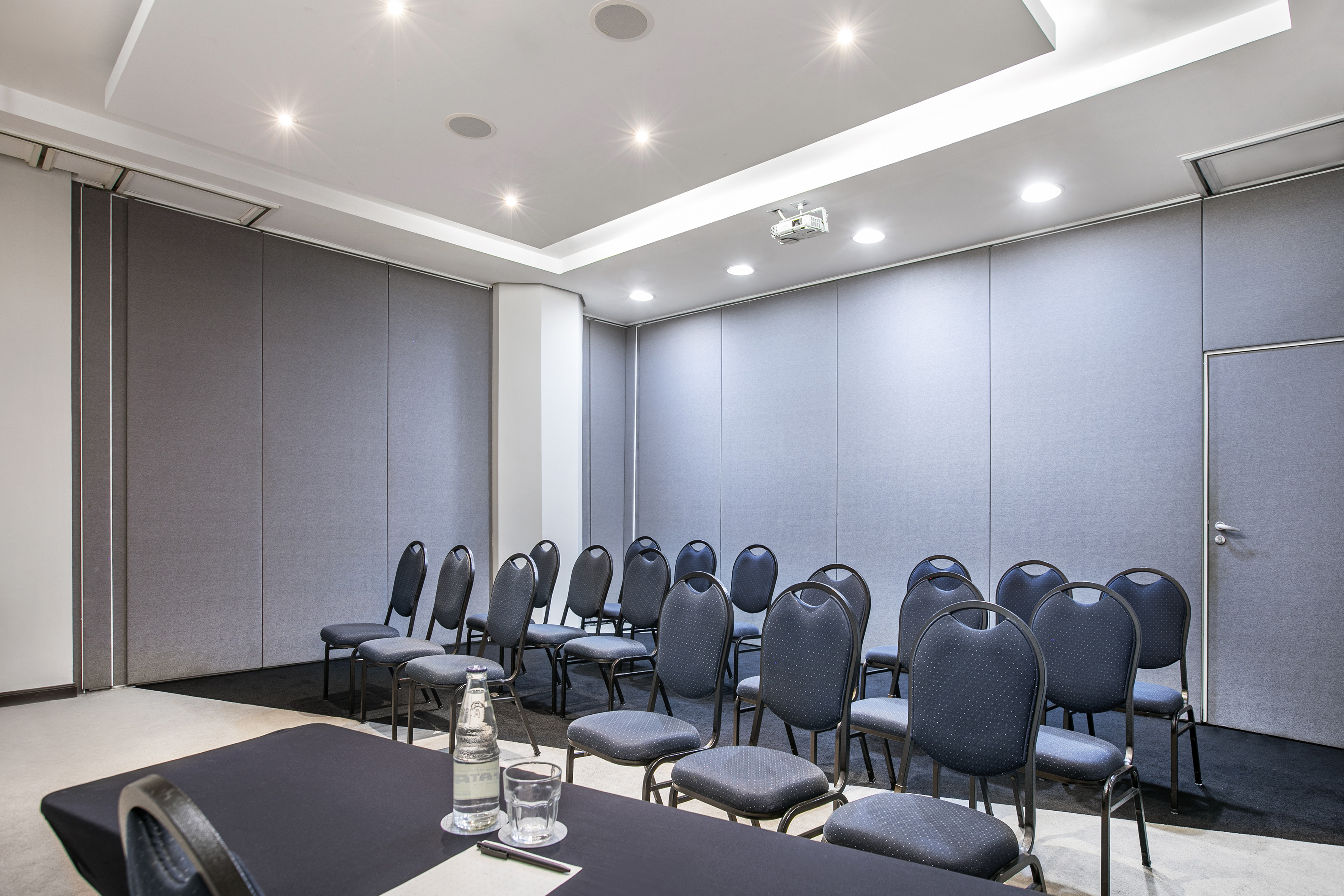 Modern conference room with grey acoustic walls, projector, and arranged seating.