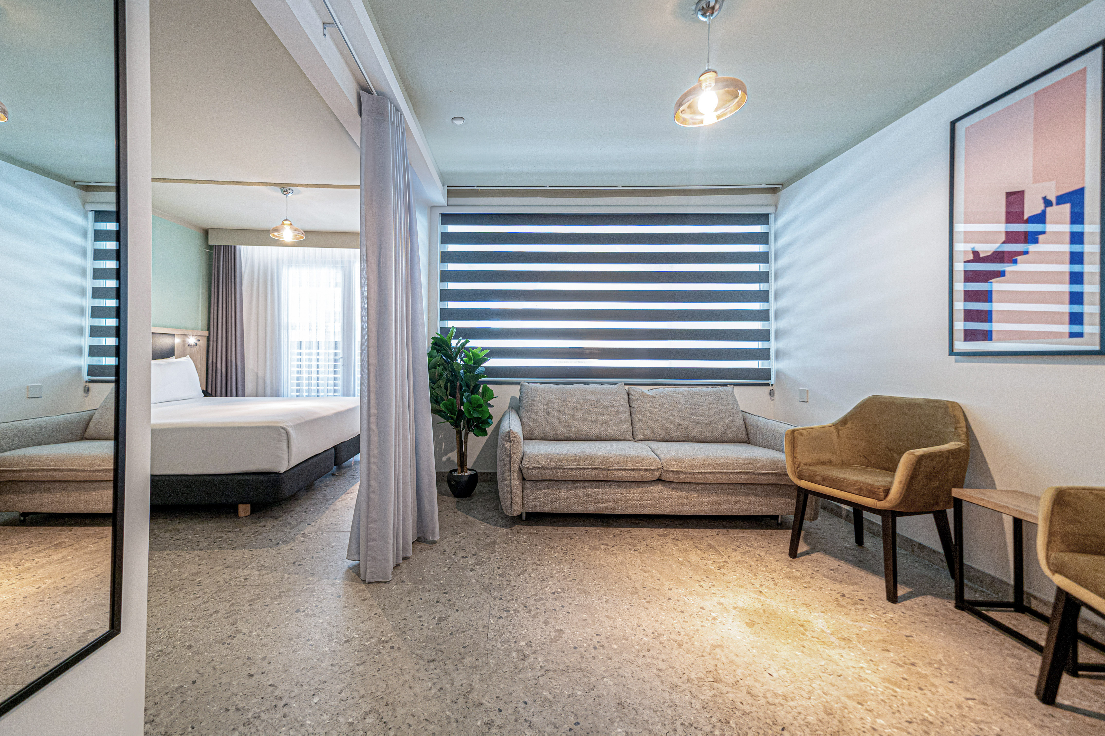 Modern studio apartment with living area, sofa, and separated bedroom.