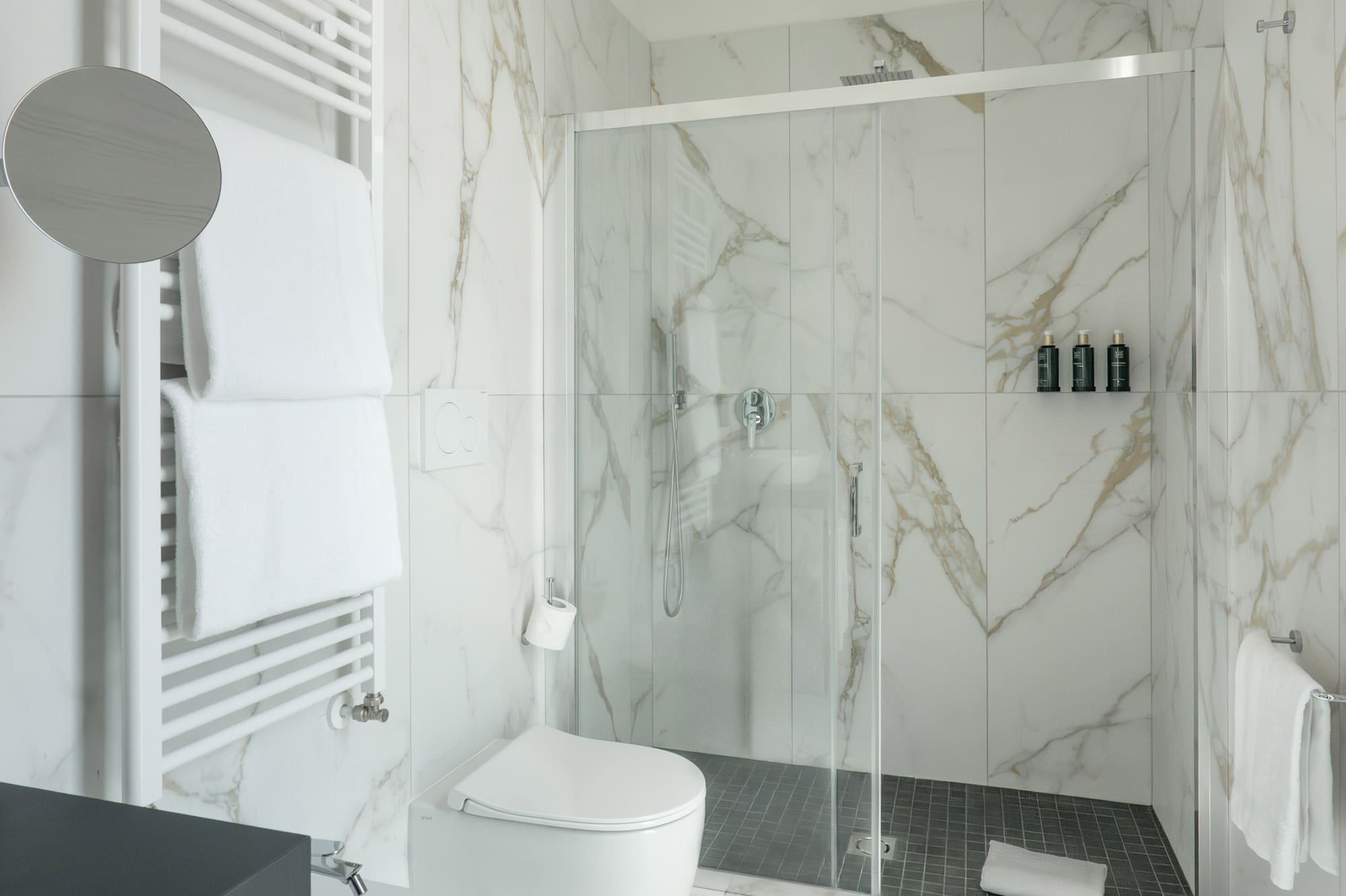 a bathroom with marble walls and a toilet and shower