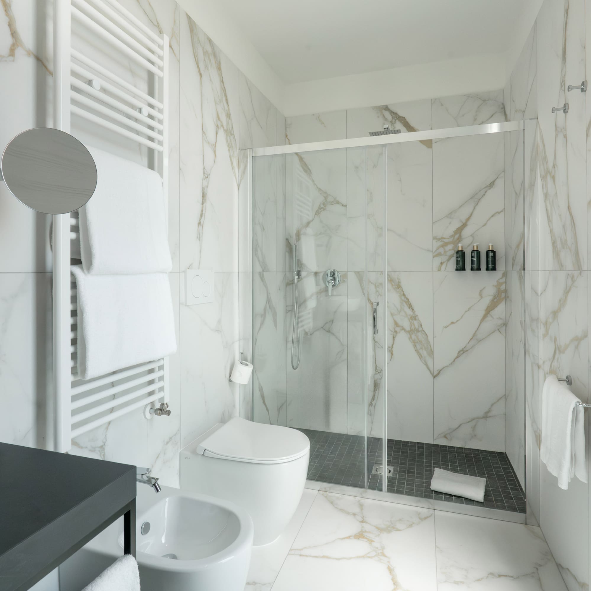 a bathroom with marble walls and a toilet and shower
