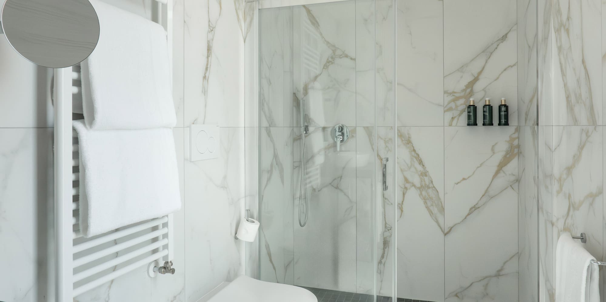 a bathroom with marble walls and a toilet and shower