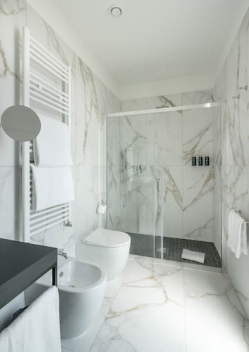 a bathroom with marble walls and a toilet and shower