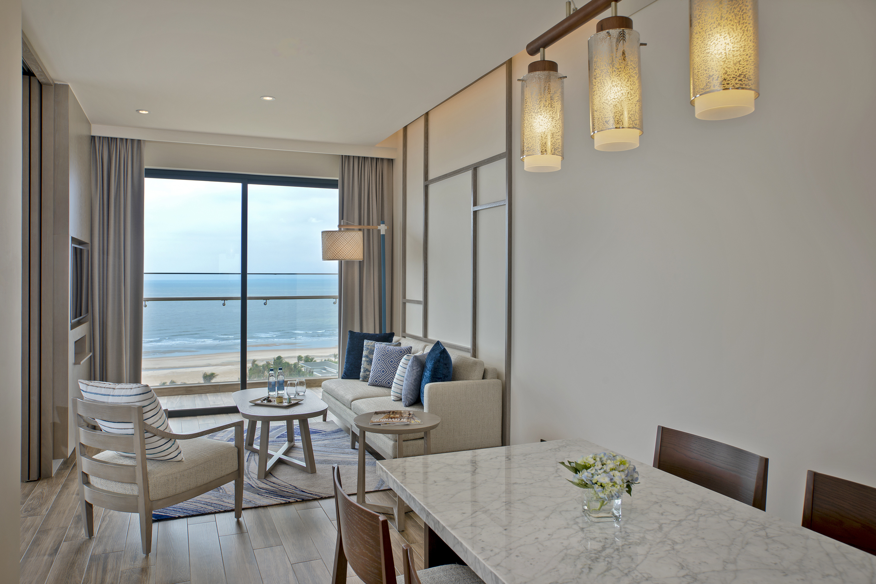 Luxury oceanfront hotel suite with modern living room and dining area.
