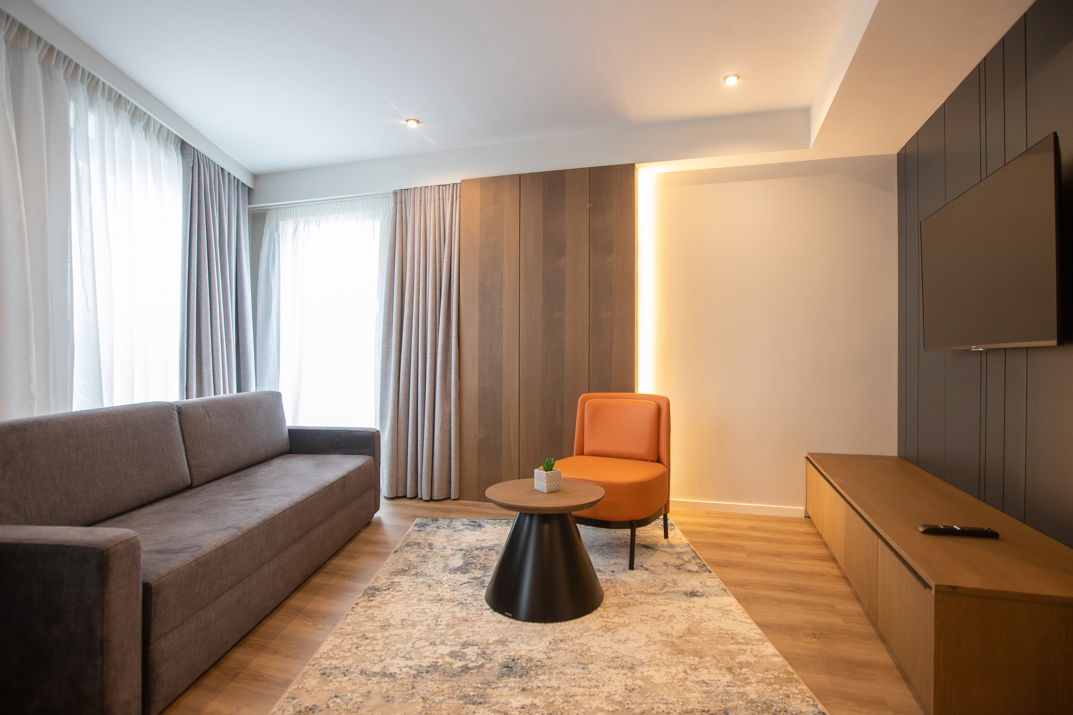 Modern living room with grey sofa, orange chair, coffee table, wood panels