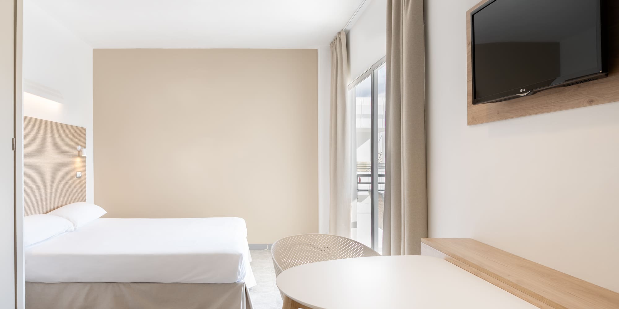 a room with a bed and a table and a television