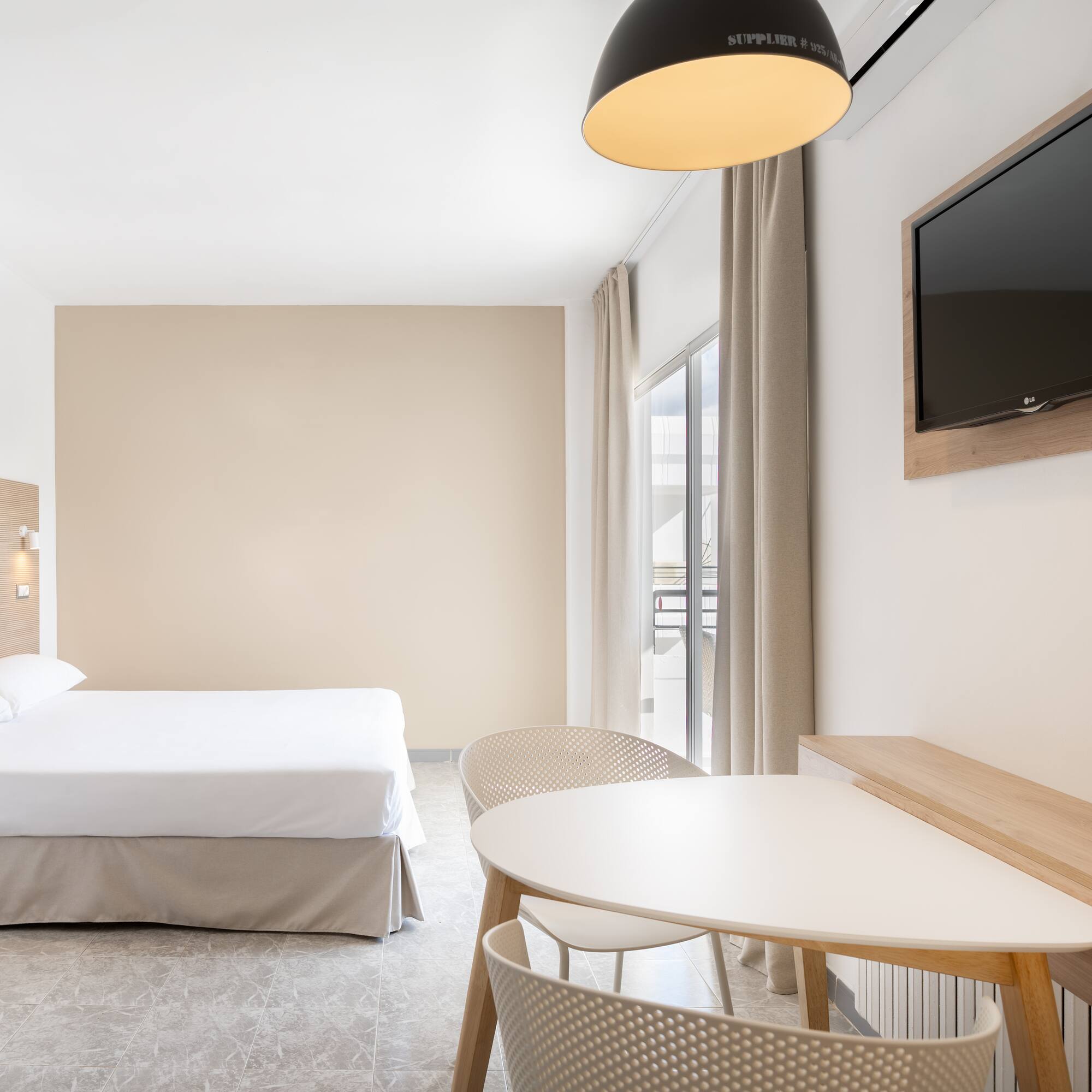 a room with a bed and a table and a television