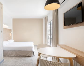 a room with a bed and a table and a television