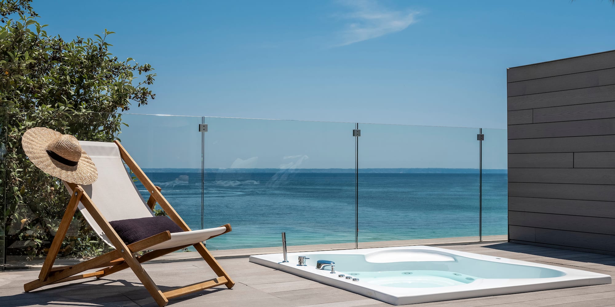 a chair on a deck with a hot tub and a glass fence