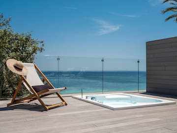 a chair on a deck with a hot tub and a glass fence