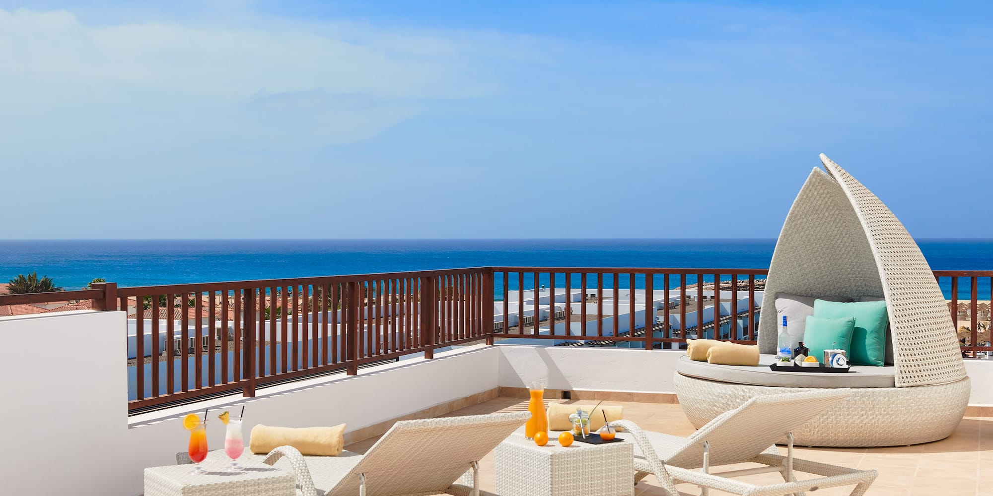 a deck with chairs and a table on a balcony overlooking the ocean