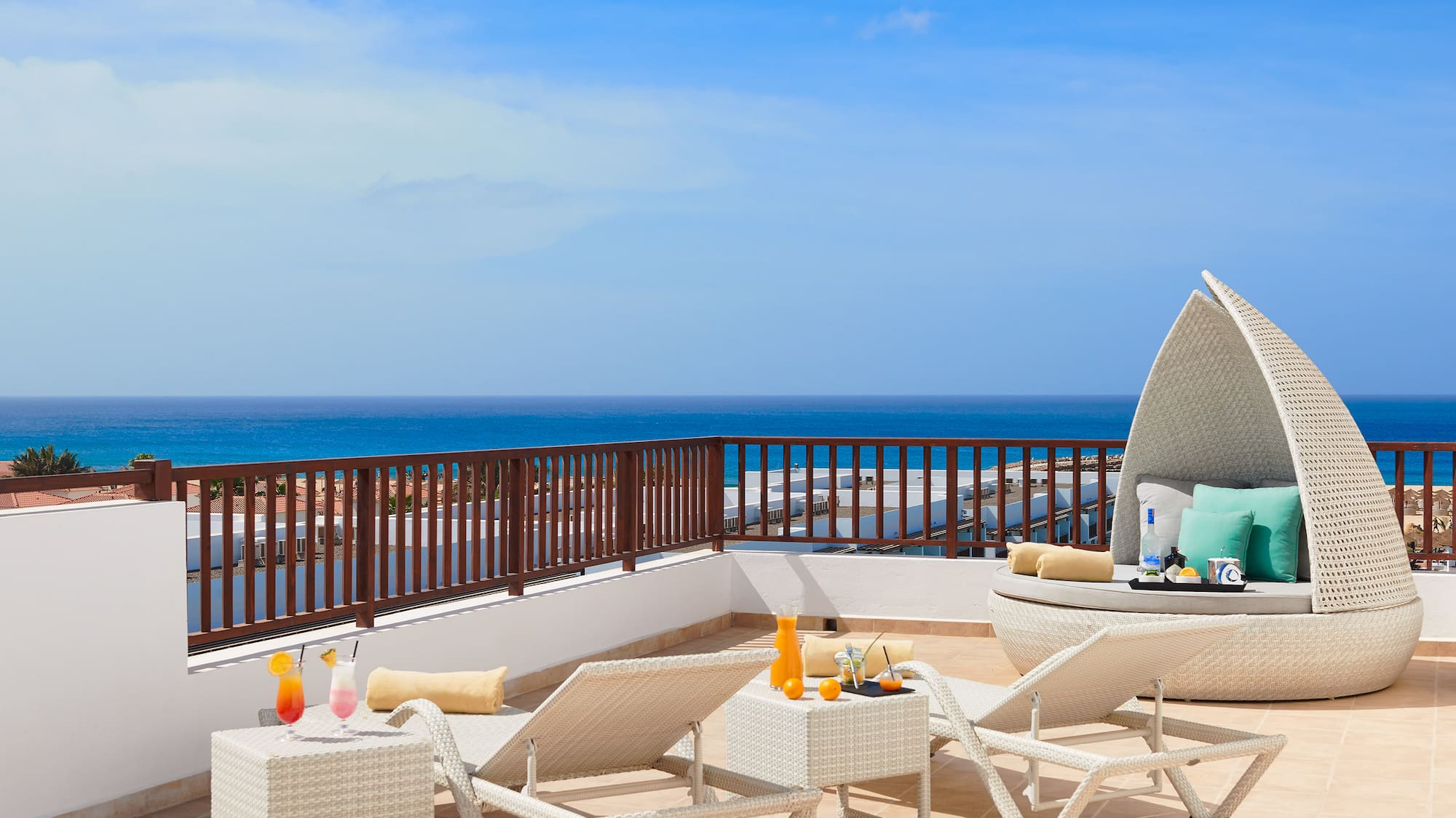 a deck with chairs and a table on a balcony overlooking the ocean