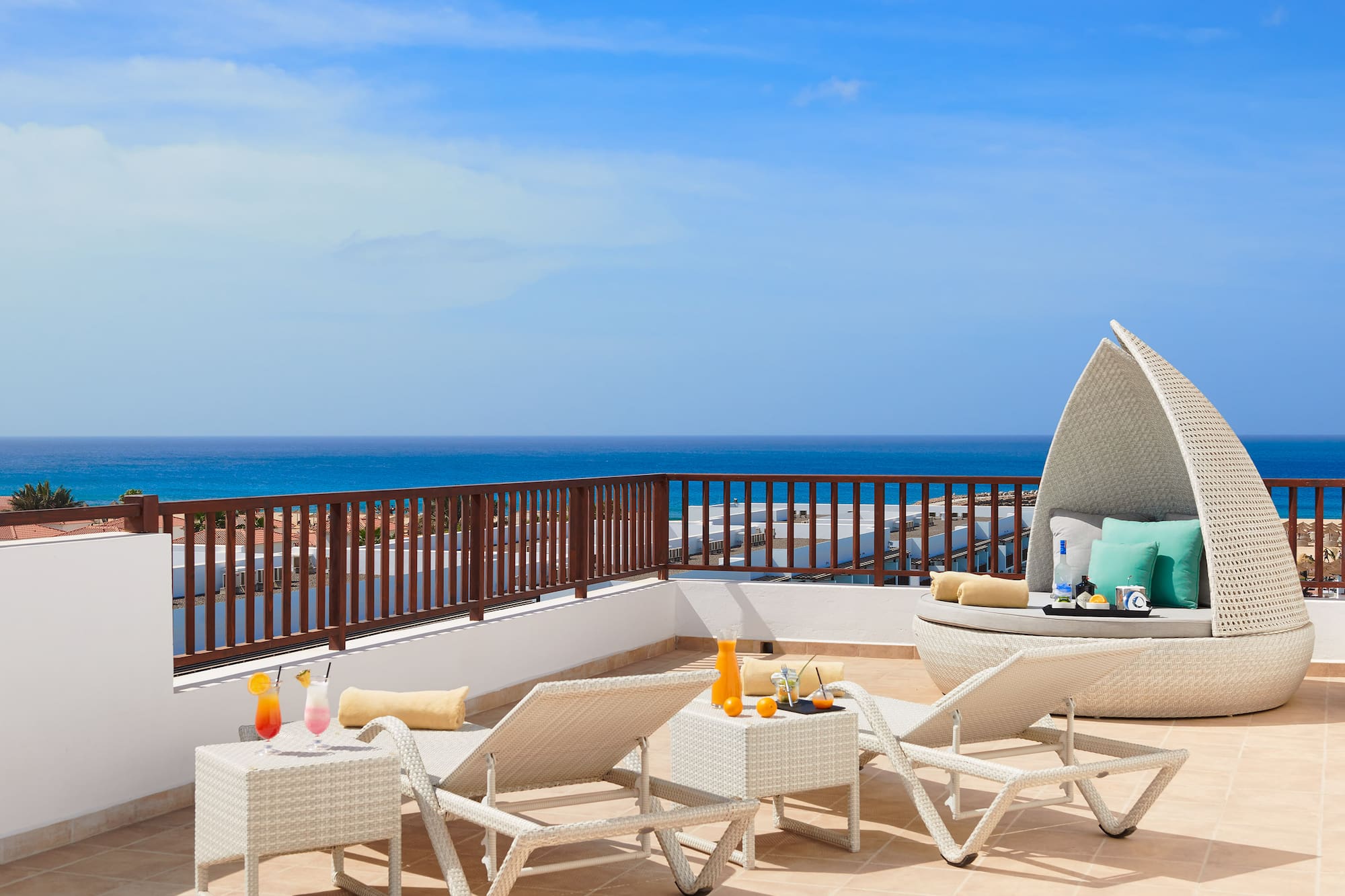 a deck with chairs and a table on a balcony overlooking the ocean