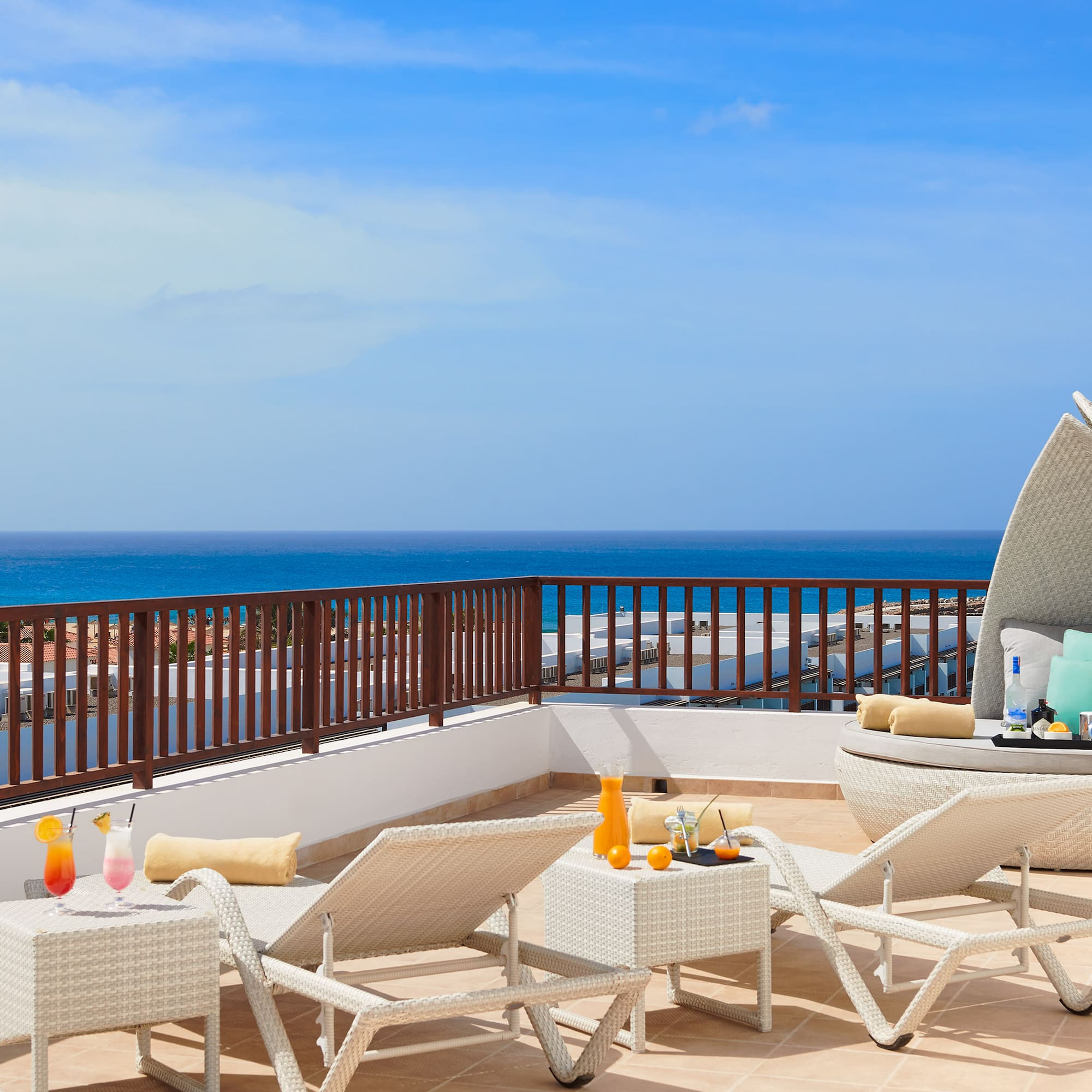 a deck with chairs and a table on a balcony overlooking the ocean