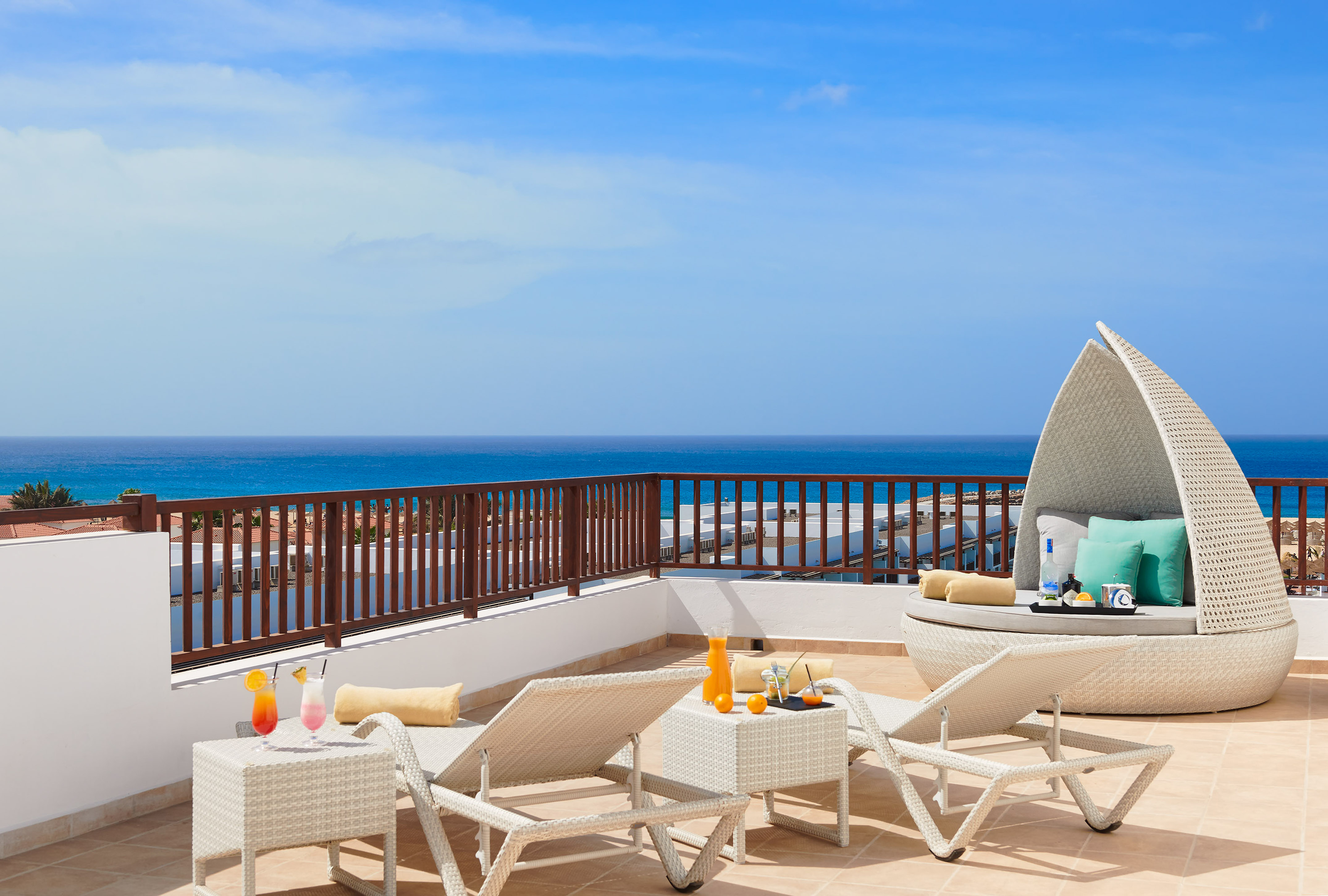 a deck with chairs and a table on a balcony overlooking the ocean