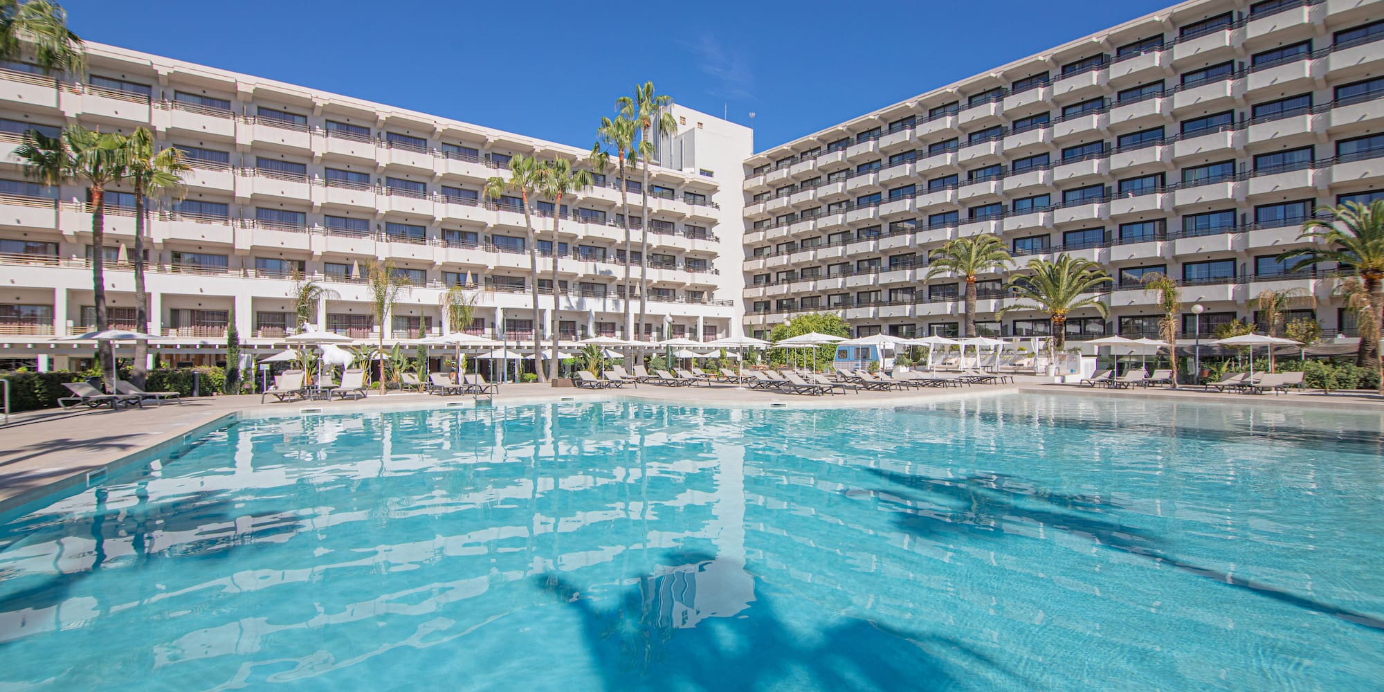 a pool with a building and palm trees