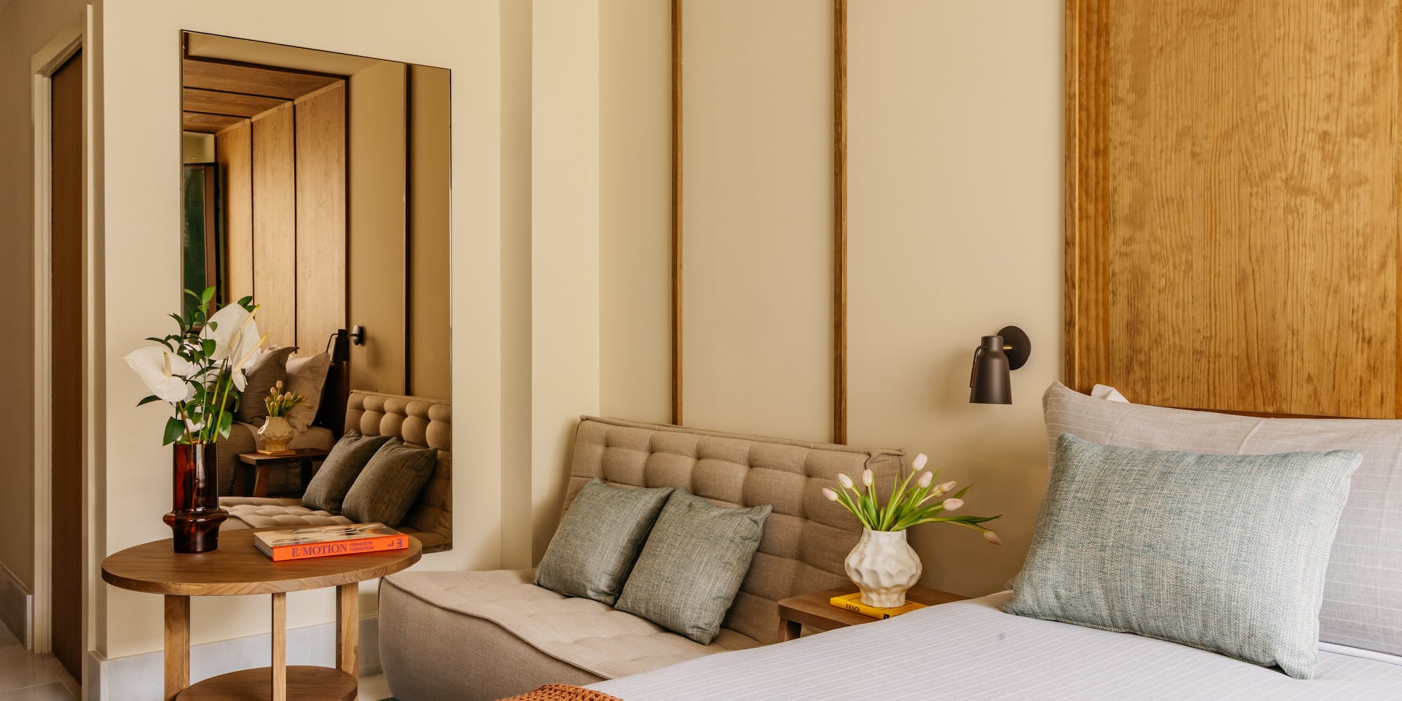 Modern bedroom with wood headboard, tufted daybed, accent tables, and decor.