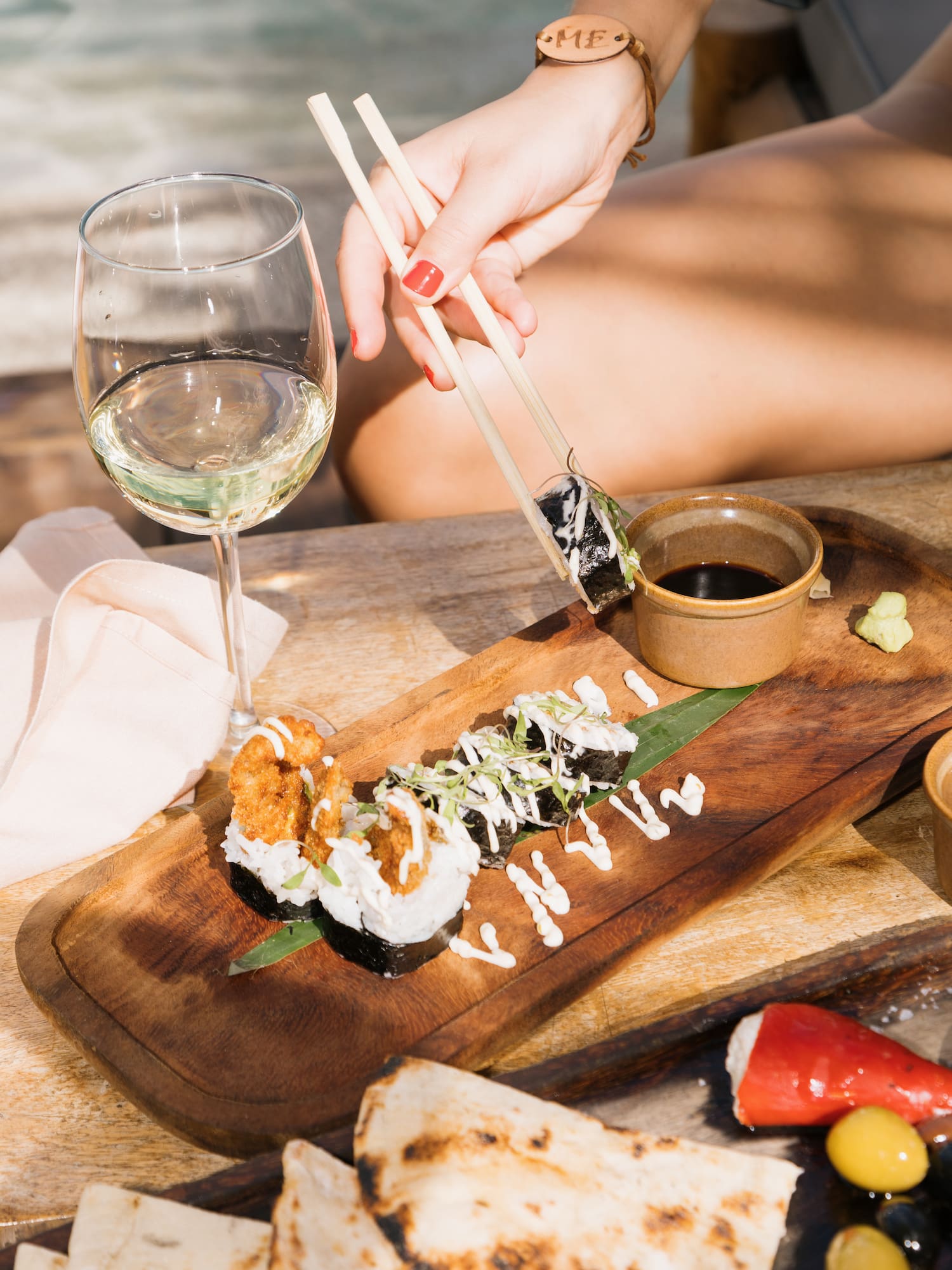 a person holding chopsticks to a plate of sushi