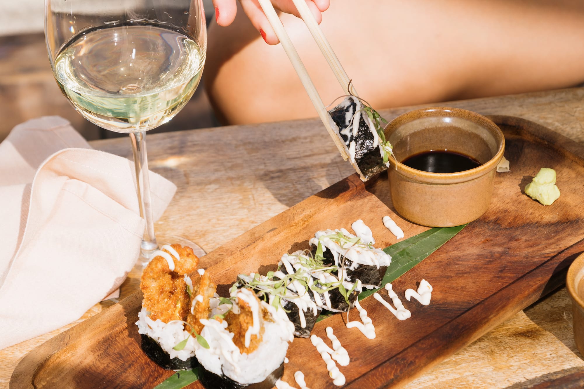 a person holding chopsticks to a plate of sushi