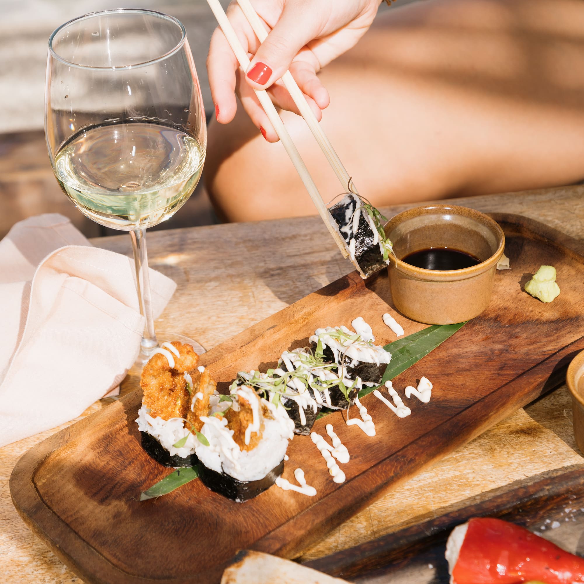 a person holding chopsticks to a plate of sushi