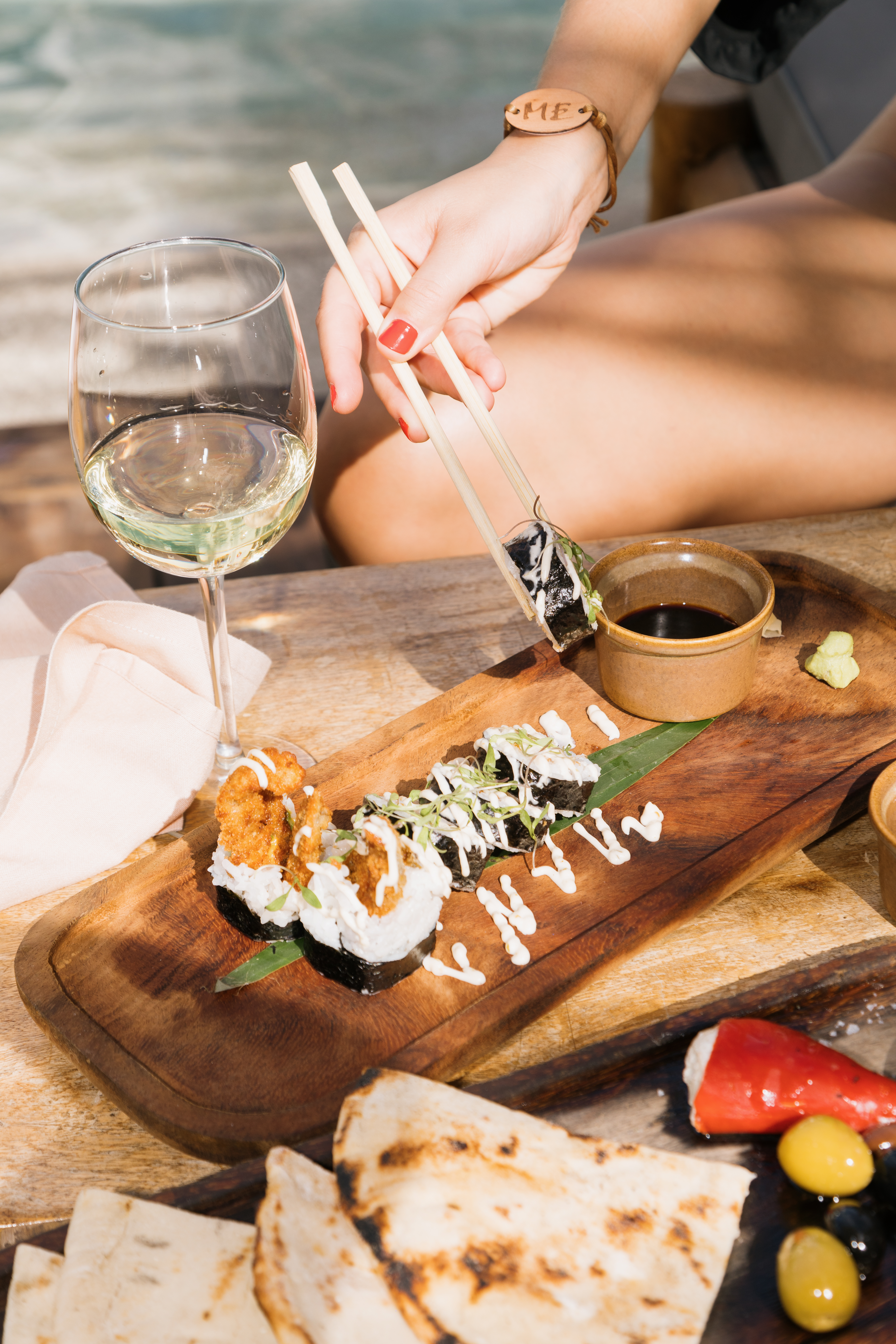 a person holding chopsticks to a plate of sushi
