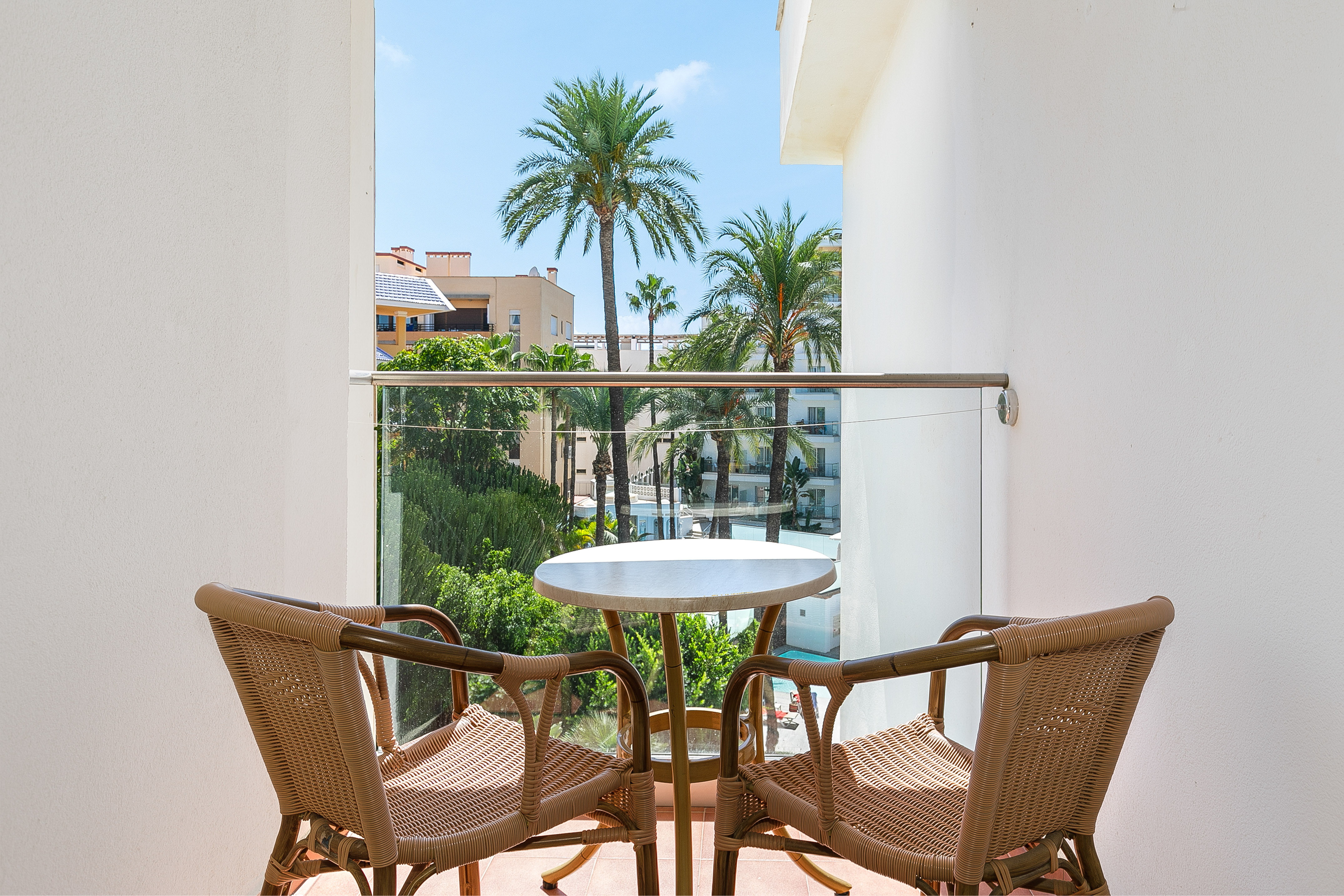 Tropical balcony with rattan furniture and palm tree view.