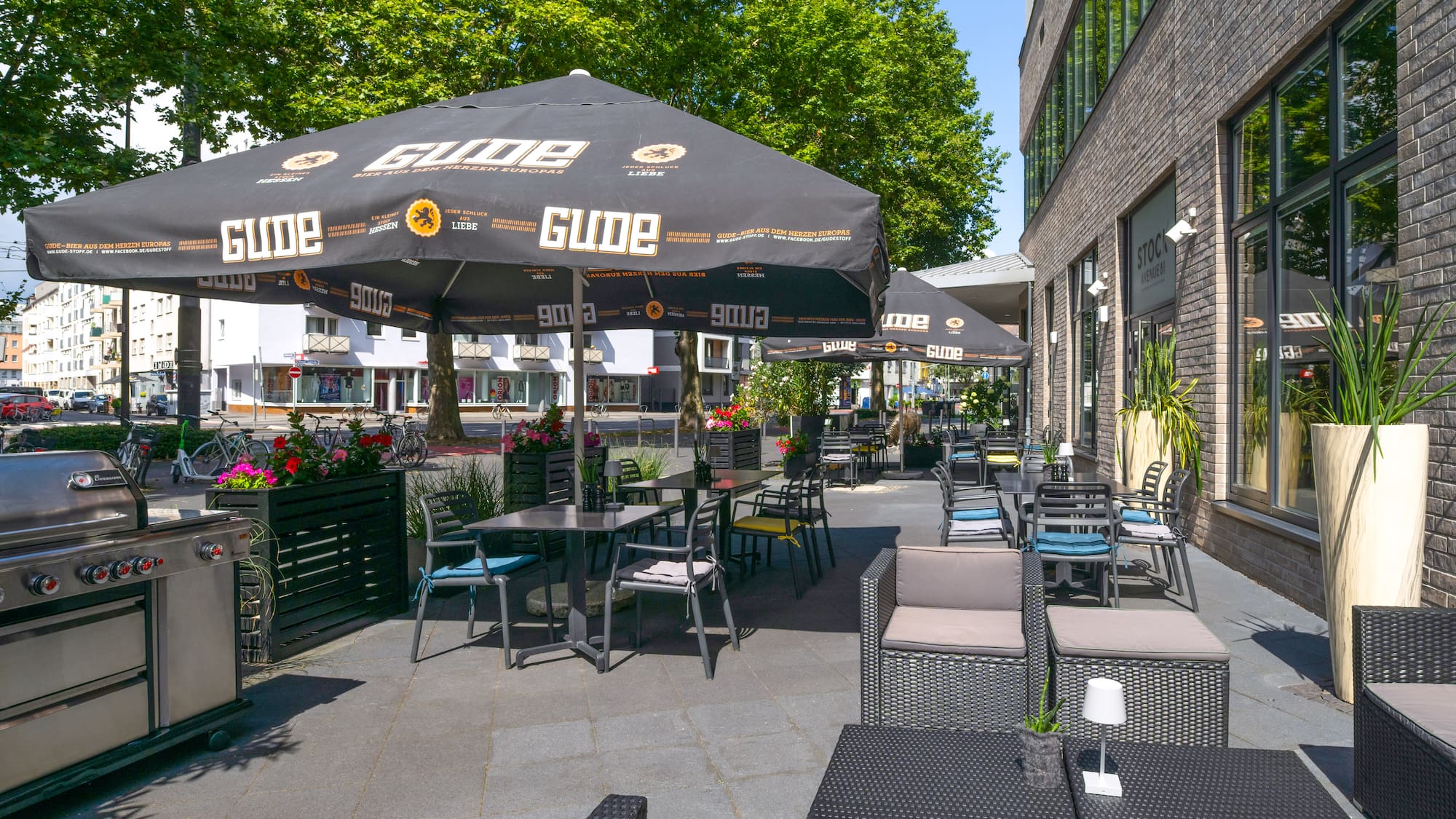 a patio with tables and chairs under an umbrella