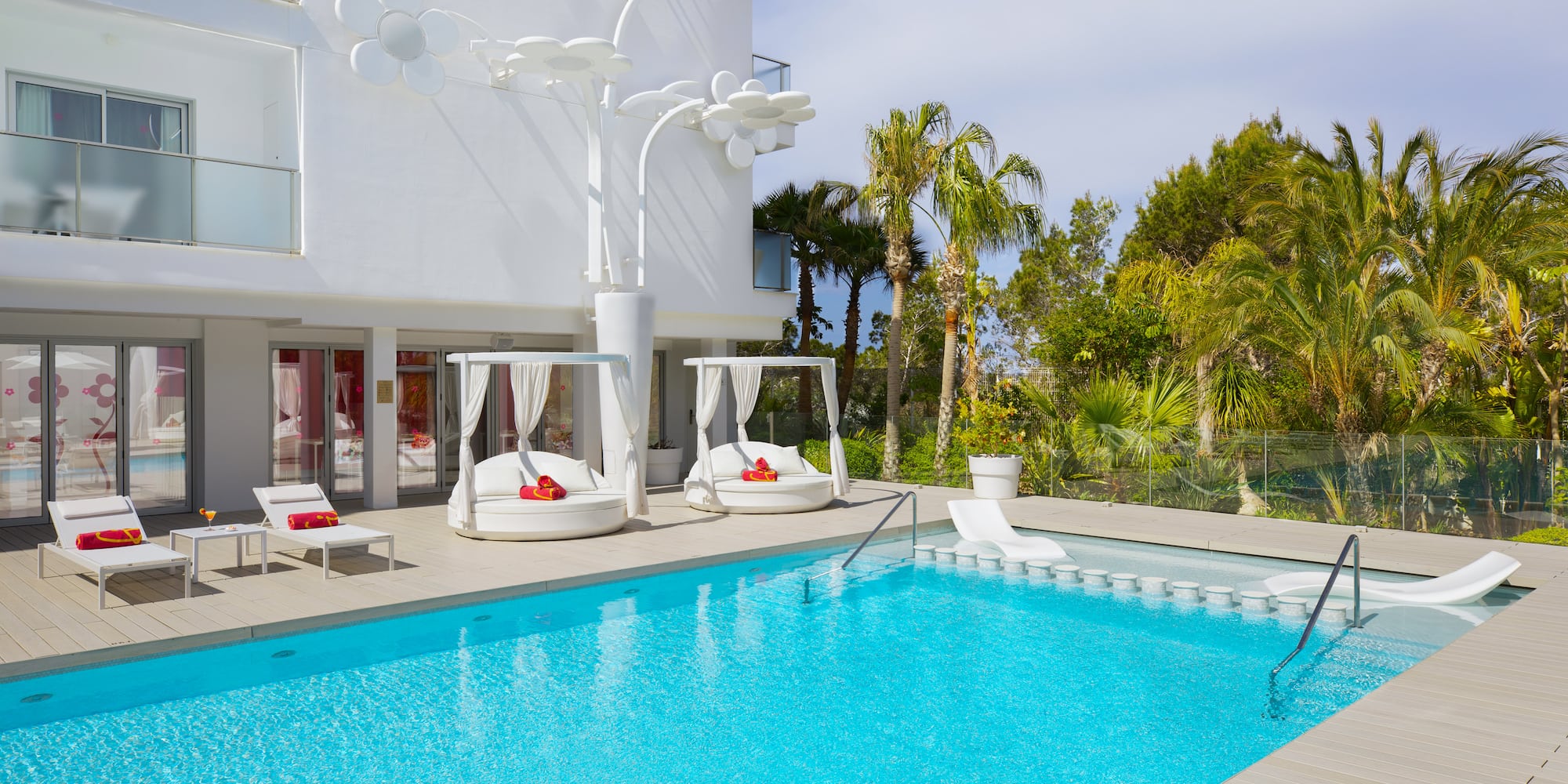 a pool with lounge chairs and a white building
