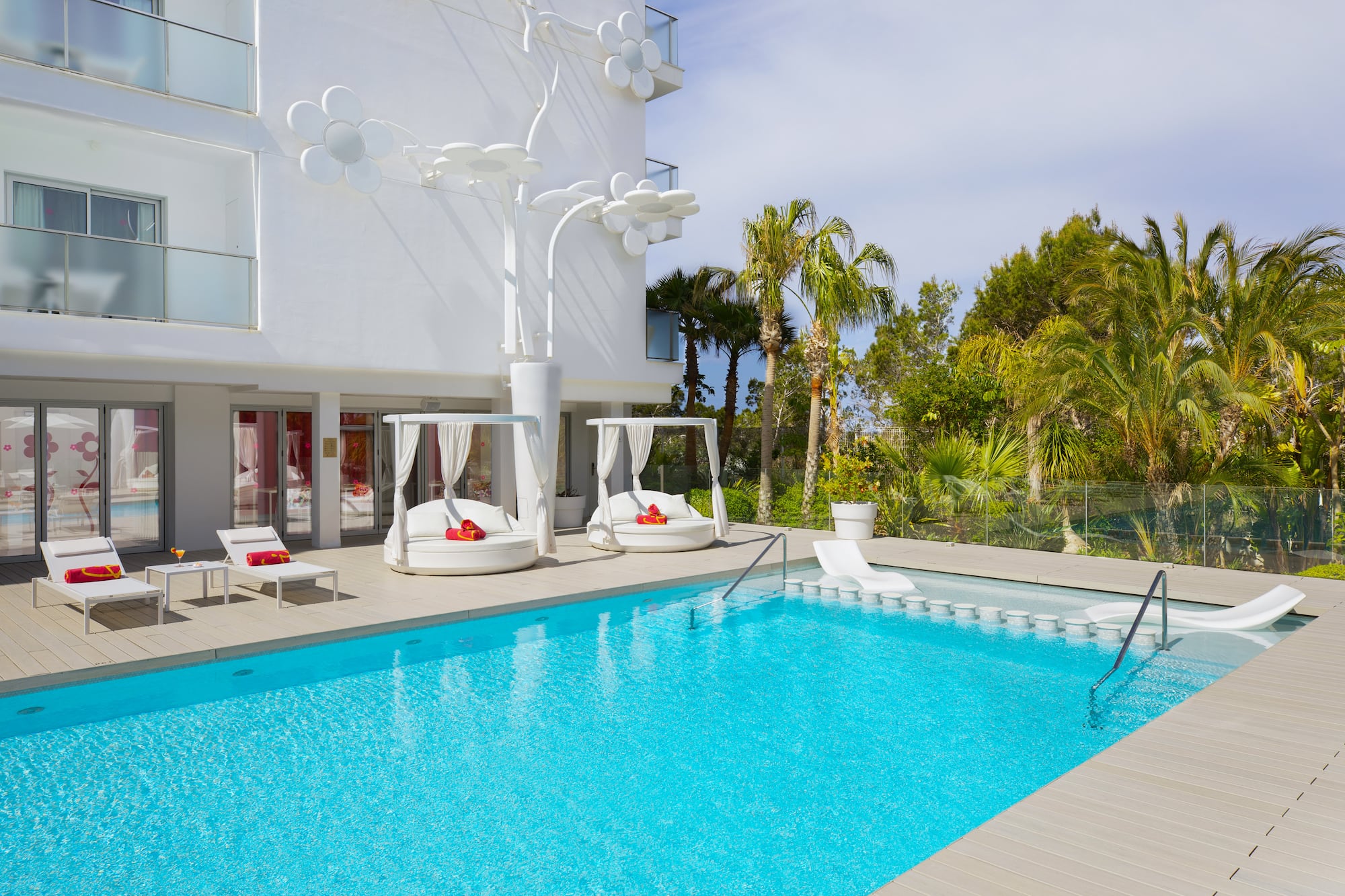 a pool with lounge chairs and a white building