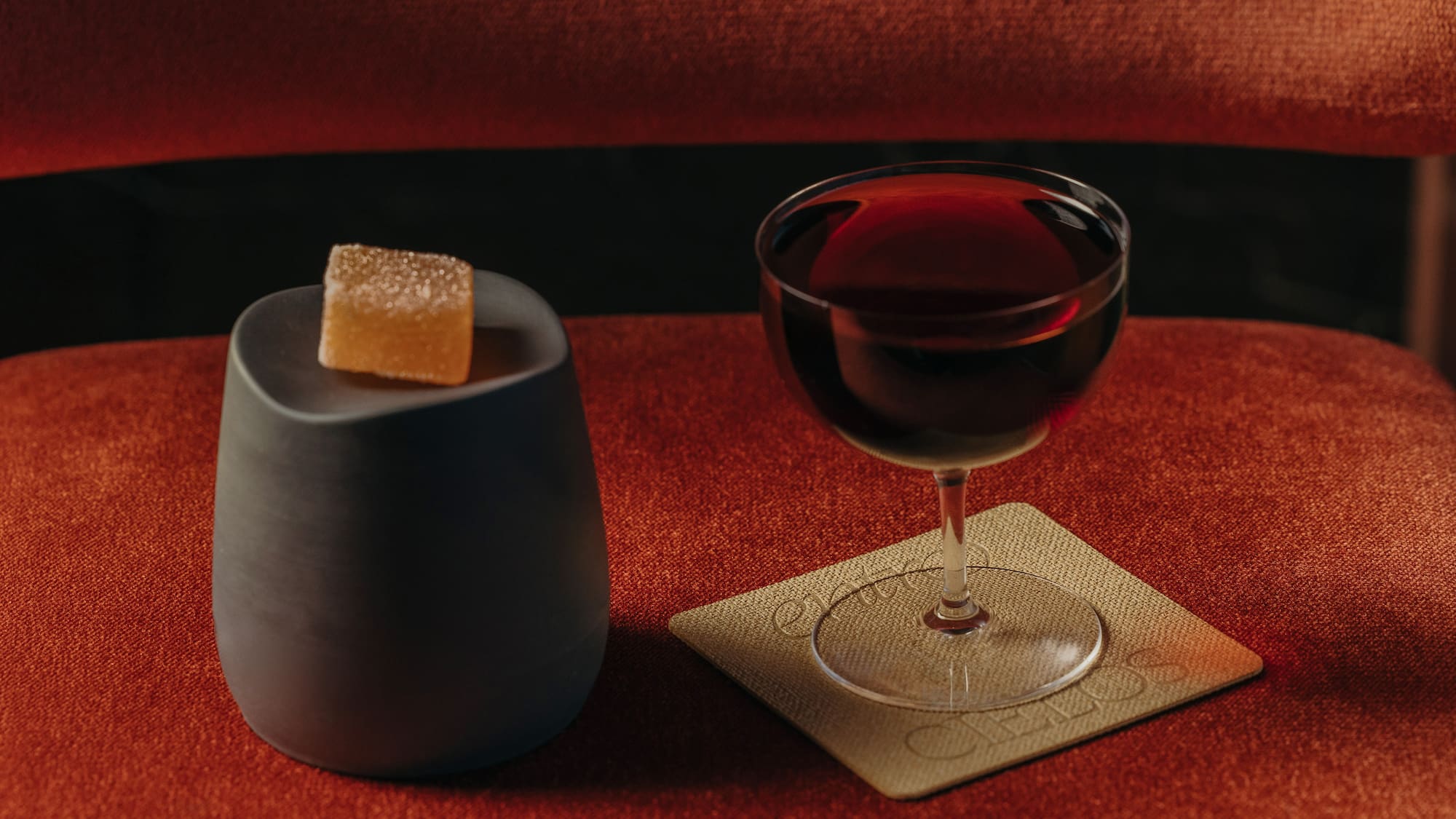 a glass of wine and a cube of brown sugar on a coaster
