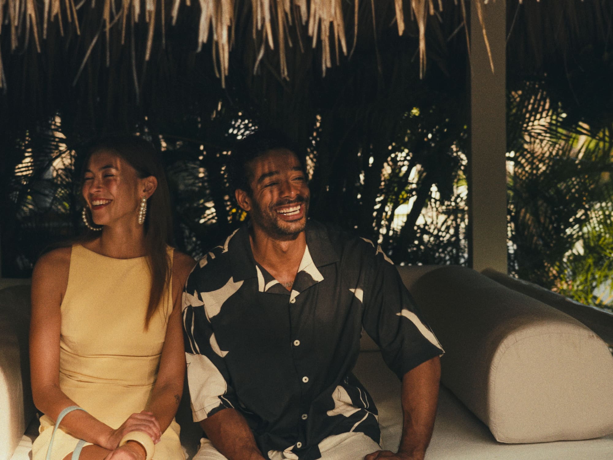 Smiling couple relaxing in a tropical resort cabana lounge.