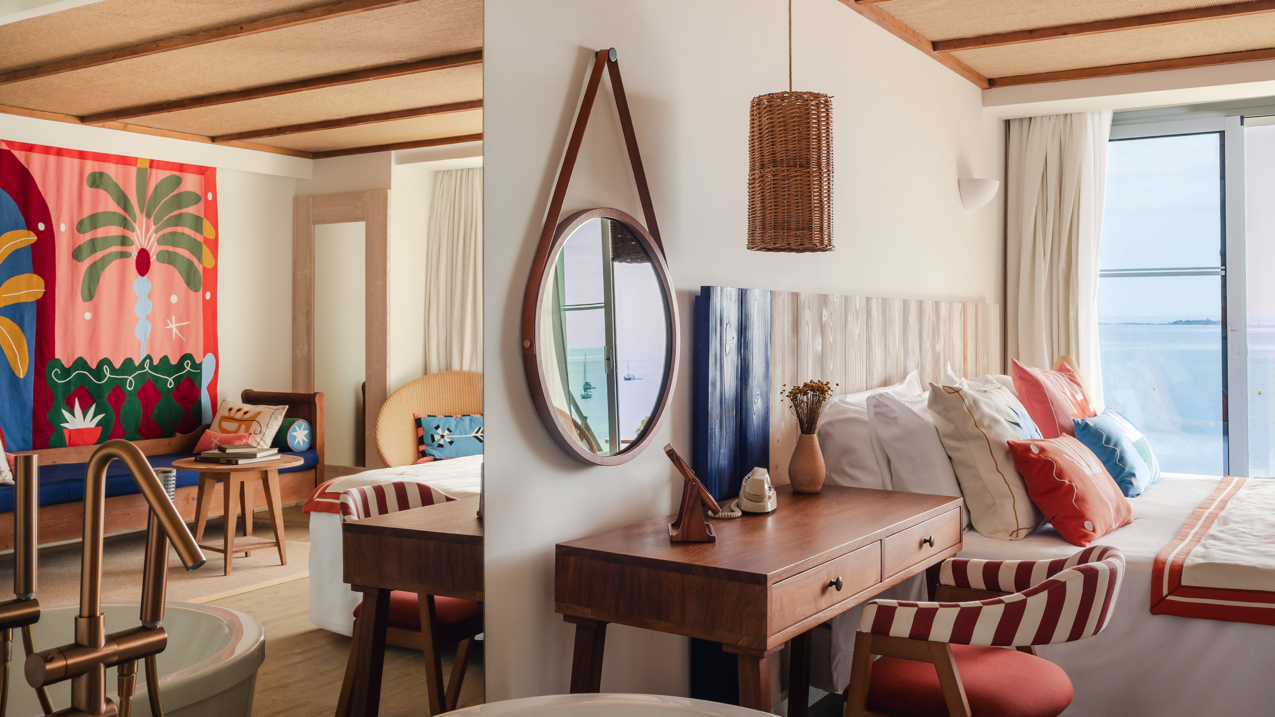 Vibrant tropical resort suite with ocean view, colorful decor, wooden furniture.