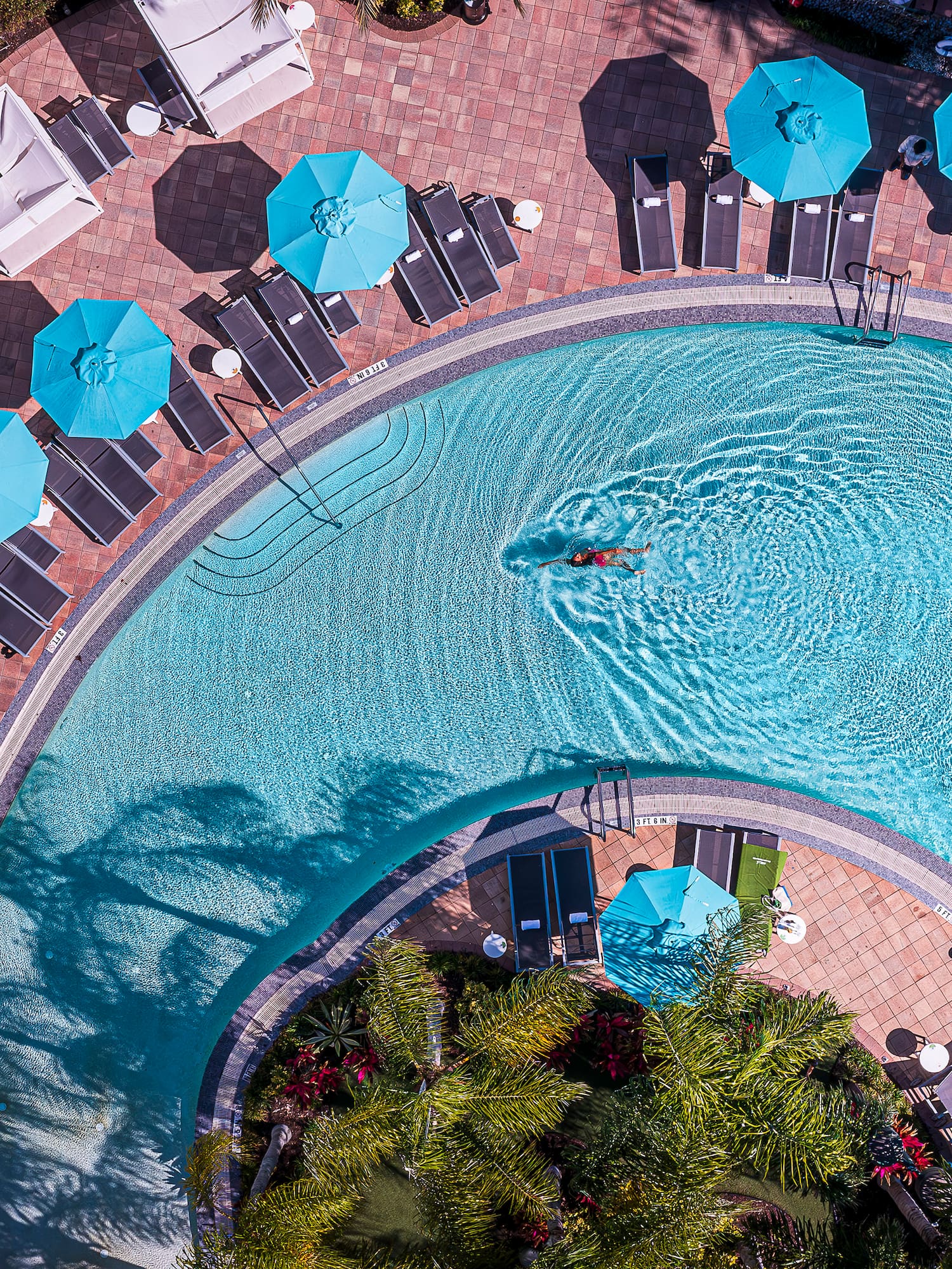 a 360 swimming pool with umbrellas and chairs.