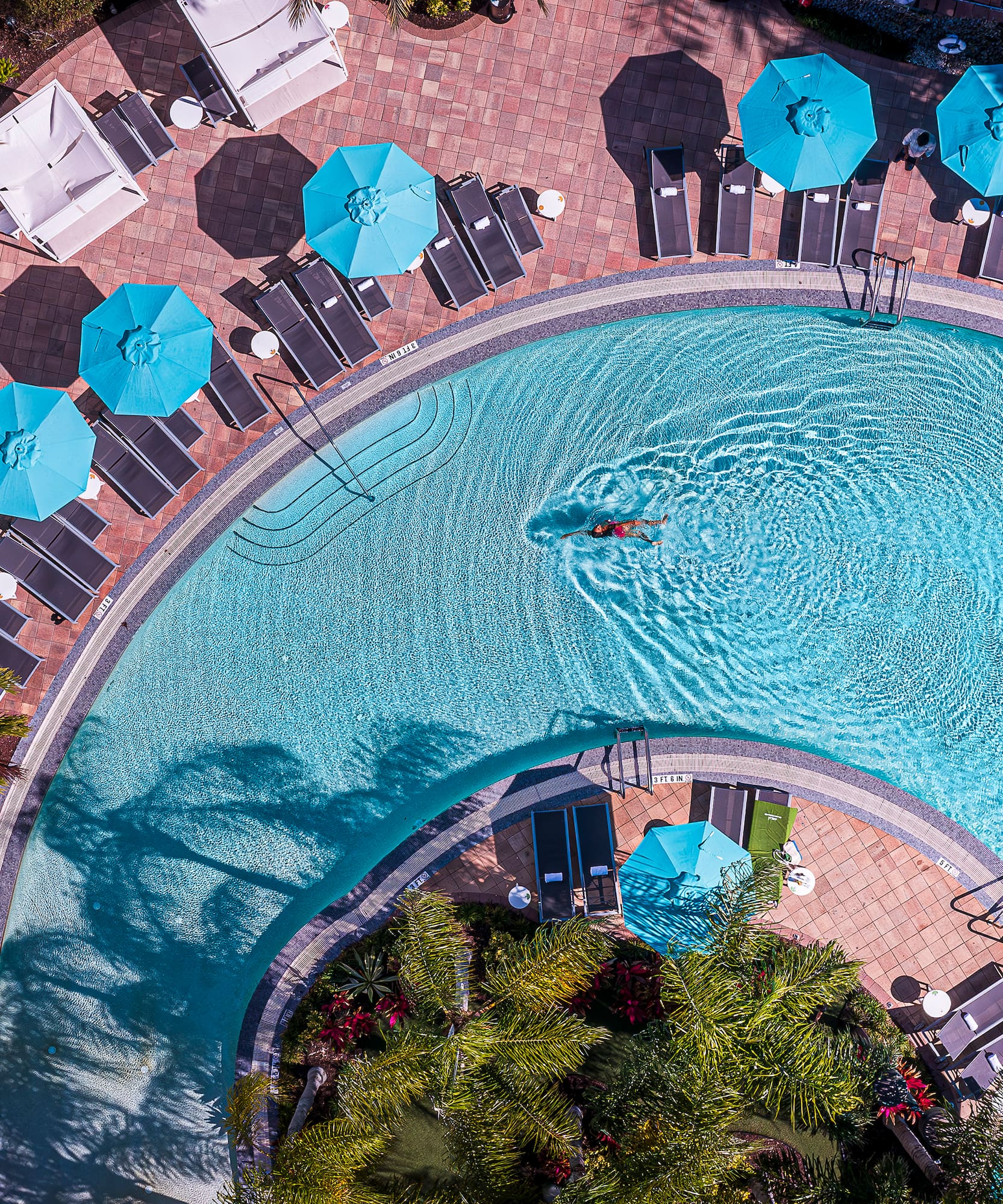 a 360 swimming pool with umbrellas and chairs.