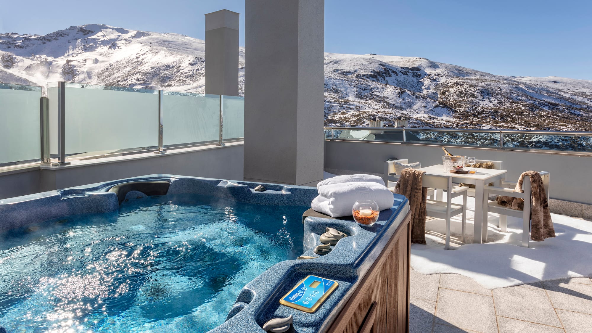 a hot tub on a rooftop with snow covered mountains in the background