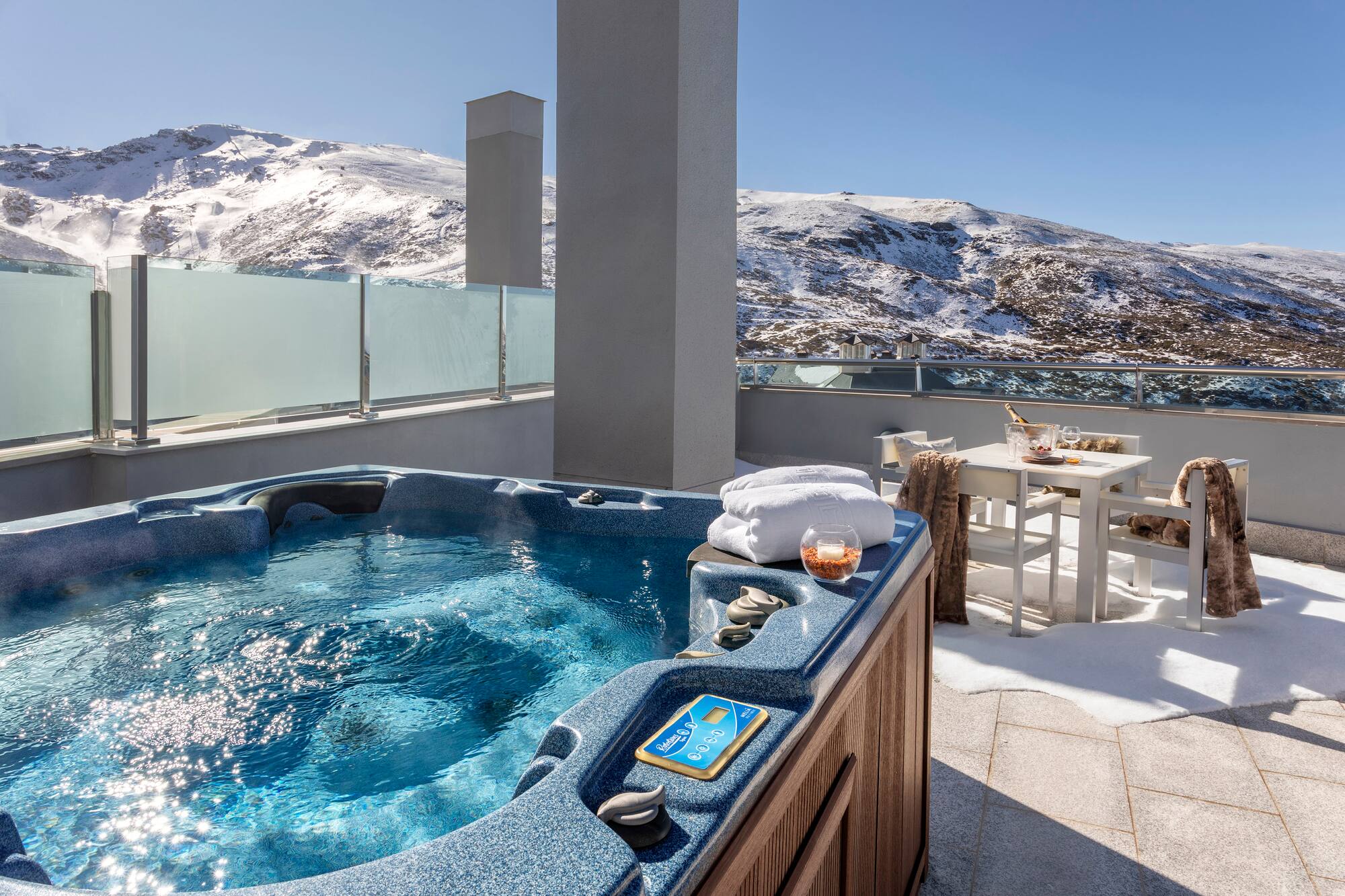 a hot tub on a rooftop with snow covered mountains in the background