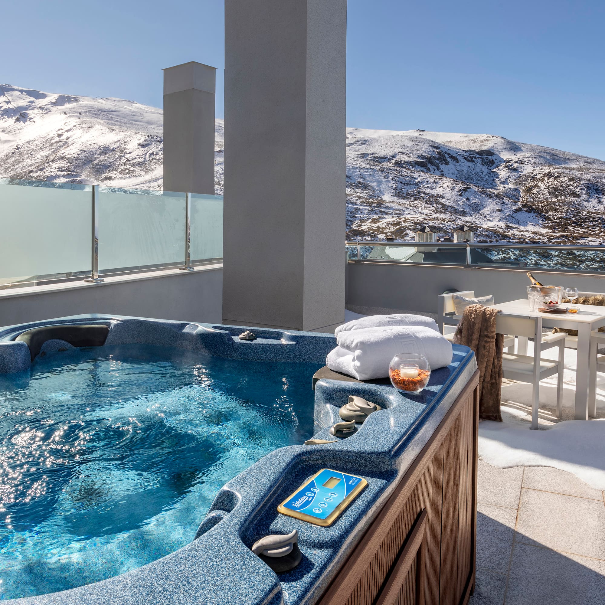 a hot tub on a rooftop with snow covered mountains in the background