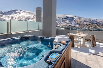 a hot tub on a rooftop with snow covered mountains in the background