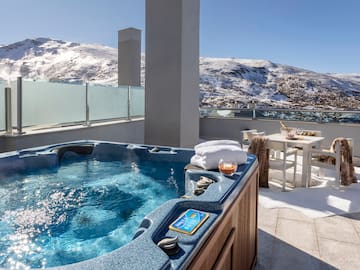 a hot tub on a rooftop with snow covered mountains in the background