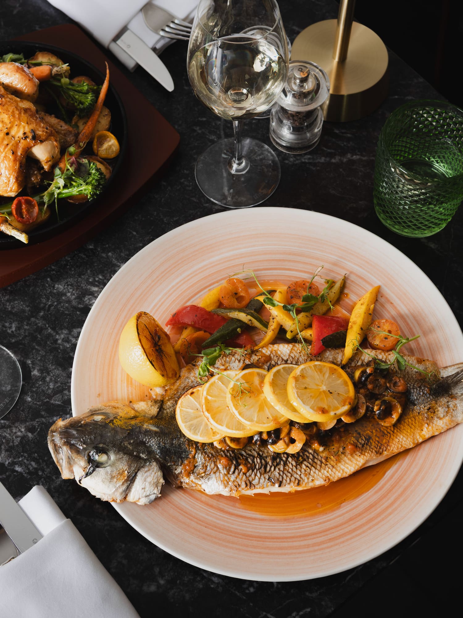 a plate of fish with lemon slices and vegetables