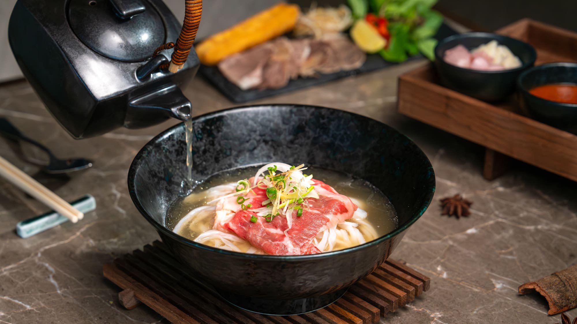 a bowl of soup with meat and noodles being poured into a teapot