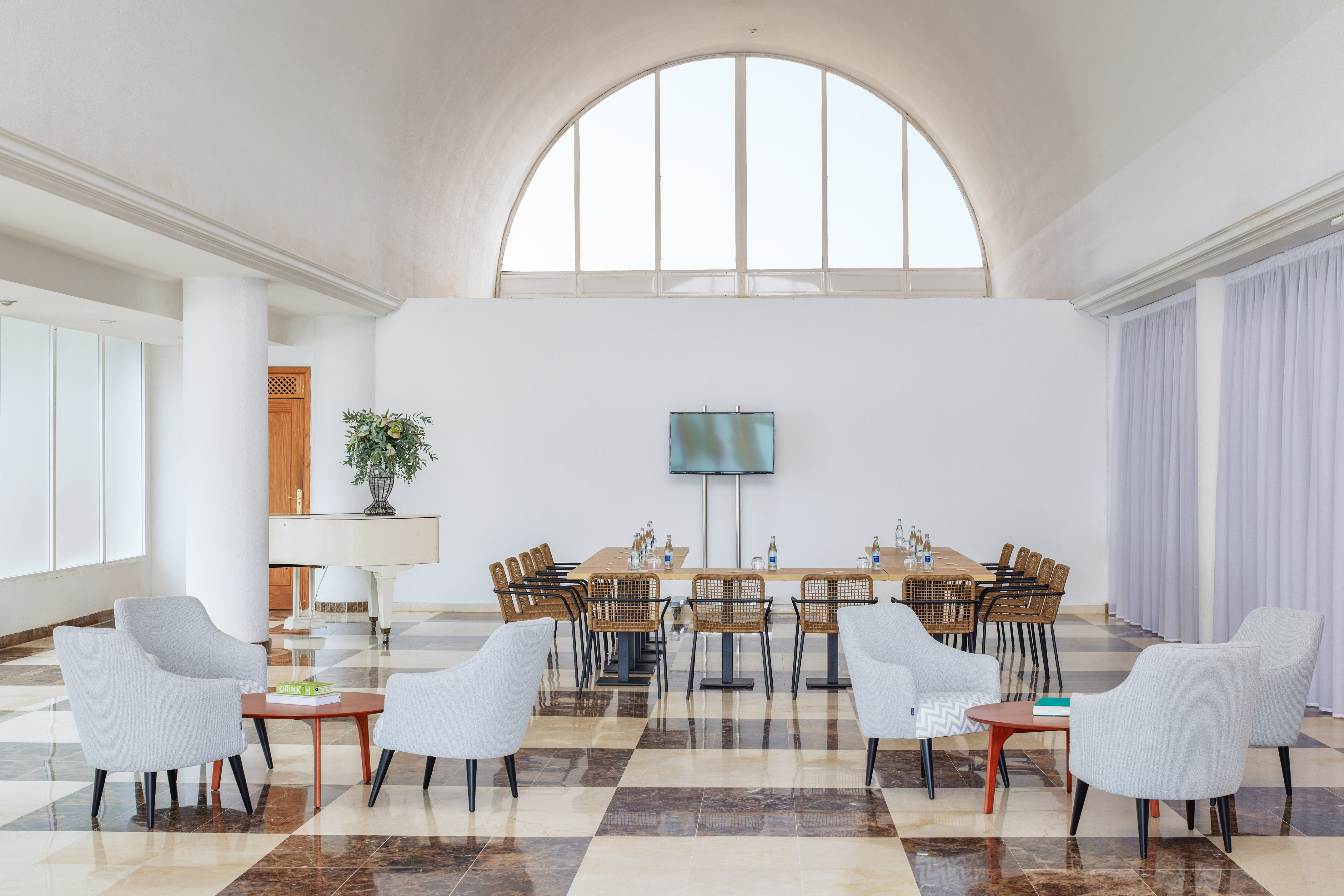 Bright conference room with long table, lounge seating, and arched window.