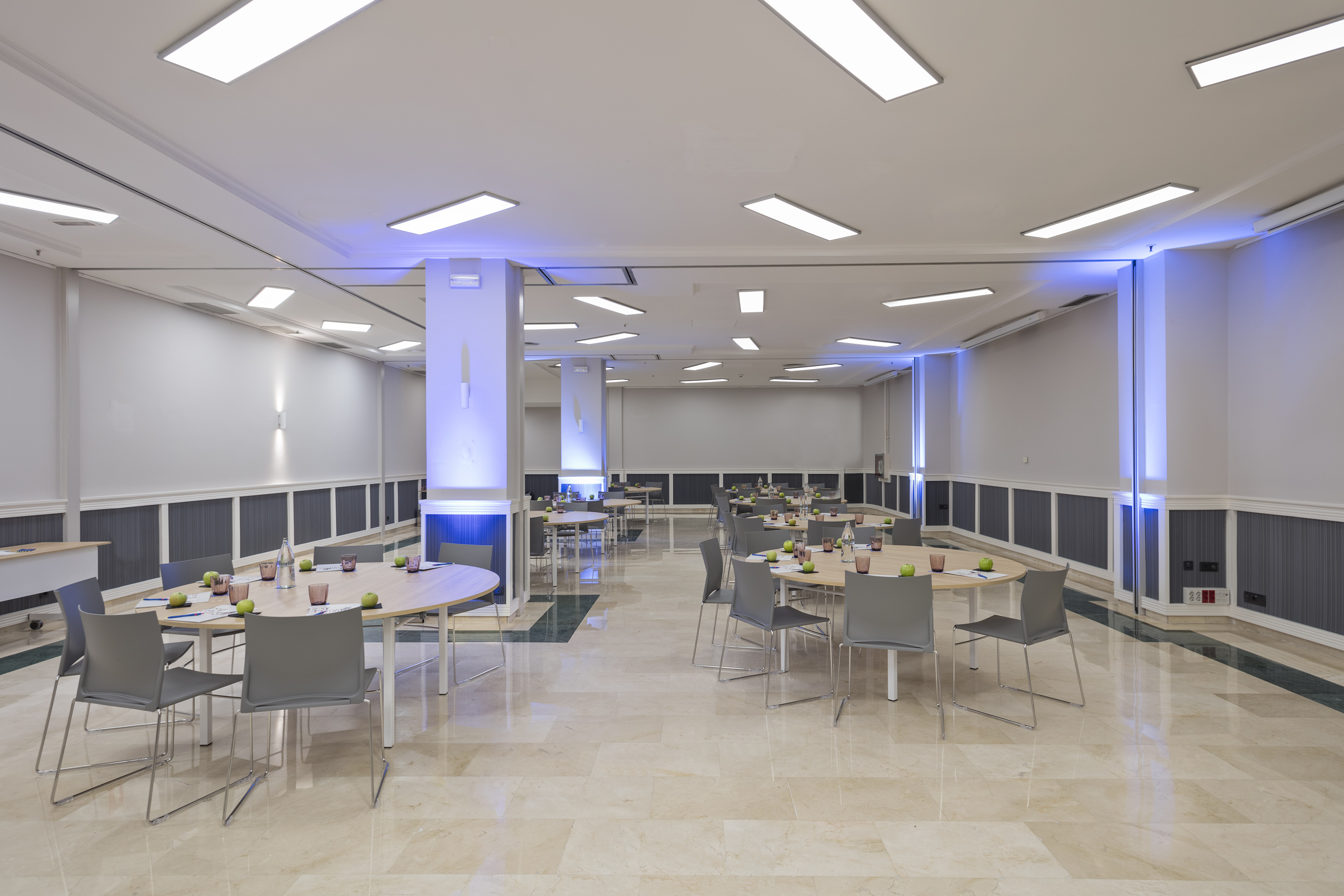 Spacious conference room with round tables, modern chairs, and blue accent lighting.