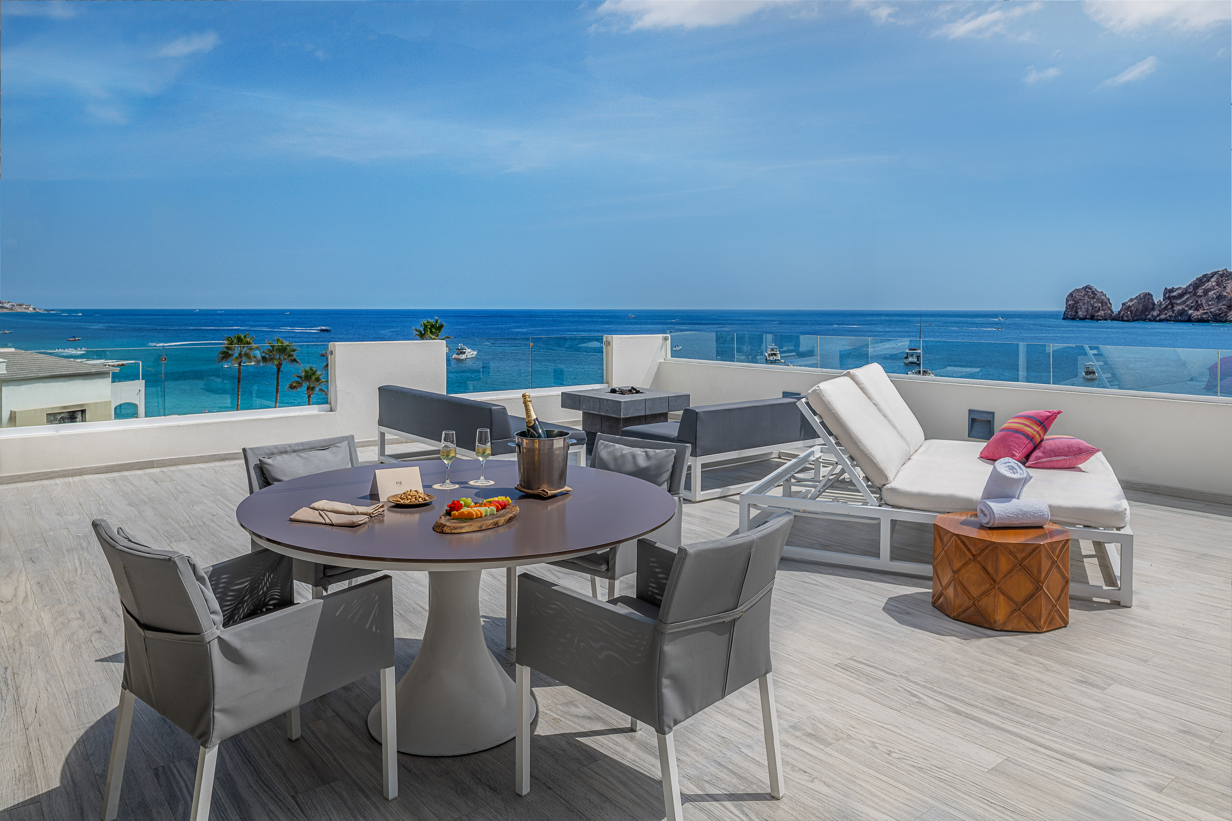 Terraza de resort con vista al mar, mobiliario exterior y champán.